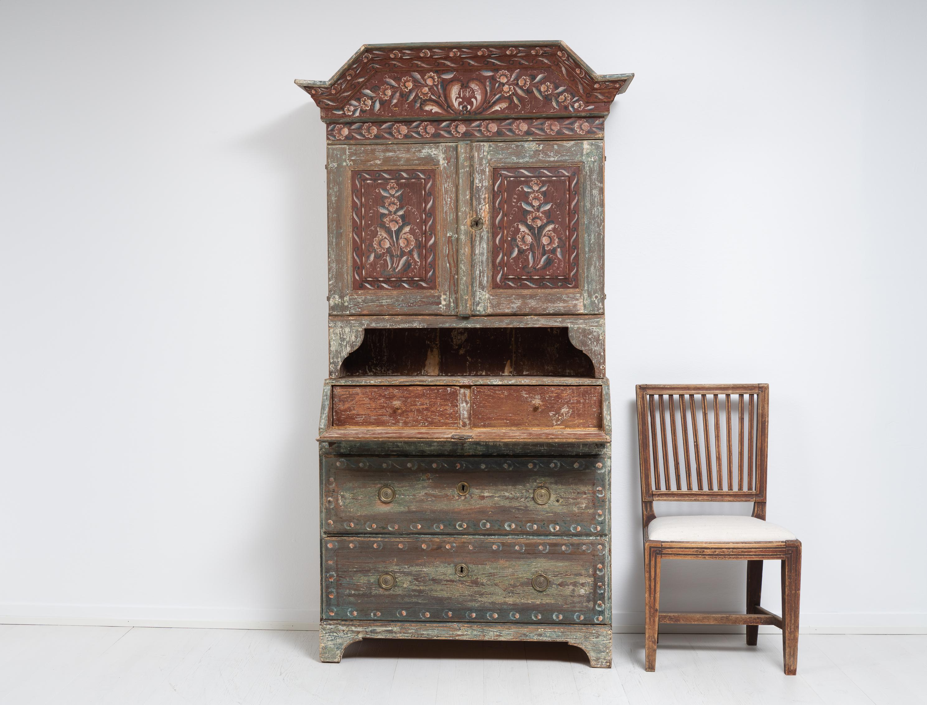 Swedish Folk Art secretary cabinet in two parts. The secretary cabinet has two large drawers, a writing desk and two upper doors with shelves inside. Original paint and dated 1818 on the pediment. The paint is distressed by time and use and has some