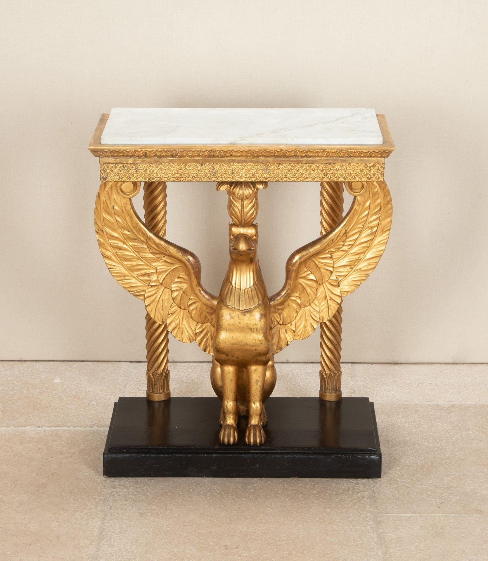 Table console en bois doré suédois du début du 19ème siècle. Le plateau en marbre de Carrare est orné d'une frise sculptée de feuillages et d'écailles de poisson stylisées. Dressé sur un griffon au repos, dans une attitude fière, les ailes