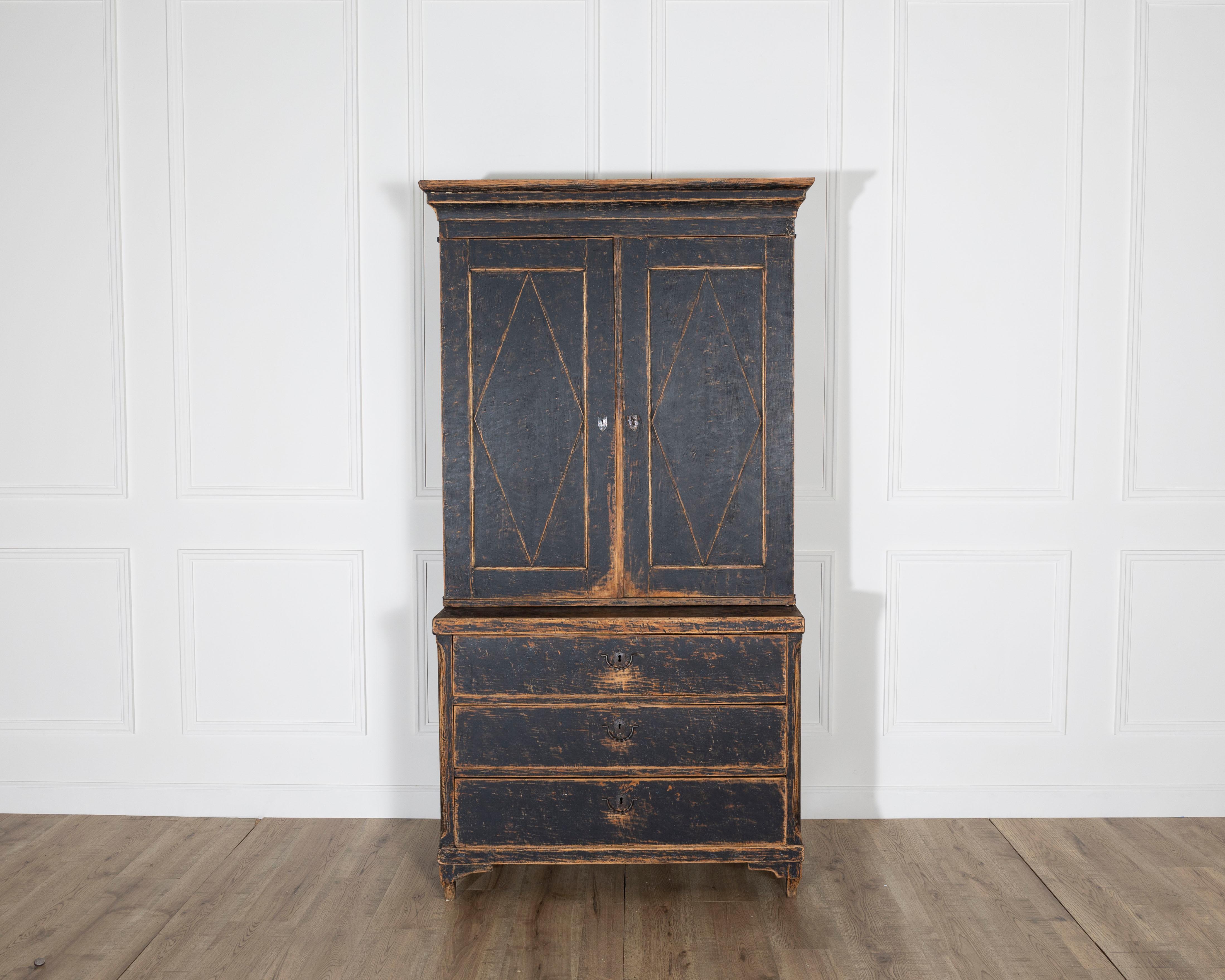 A striking two-part cabinet from Värmland, Sweden, dating to the early 19th century, embodying the quiet elegance of the Gustavian period. This finely crafted piece showcases classic neoclassical proportions with clean geometric door panels, fluted