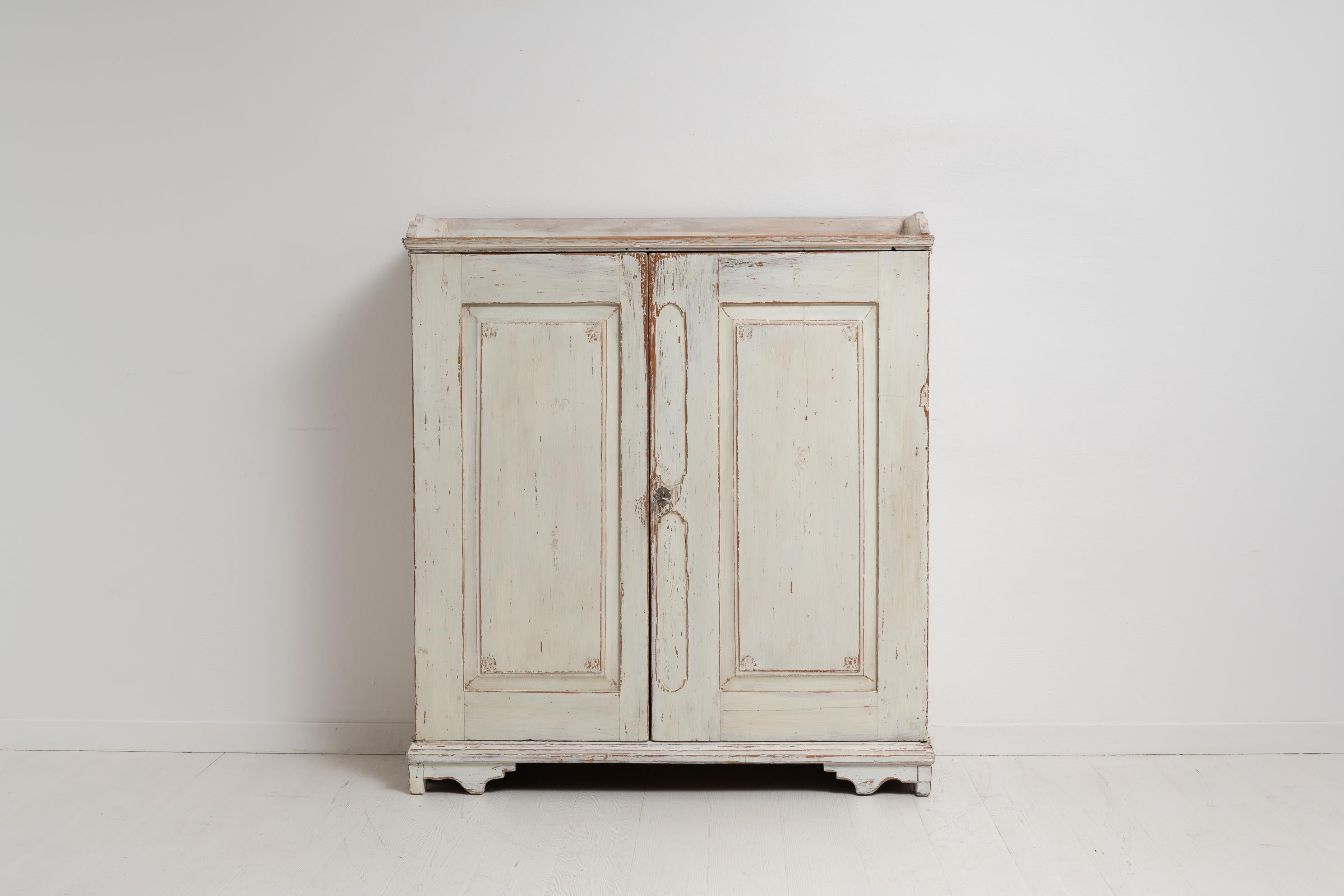 Swedish country home sideboard in gustavian style from the early 19th century. This country furniture is from around 1820 to 1830 and made in painted pine. The interior has multiple small drawers as well as 3 shelves. Old renovation with paint from