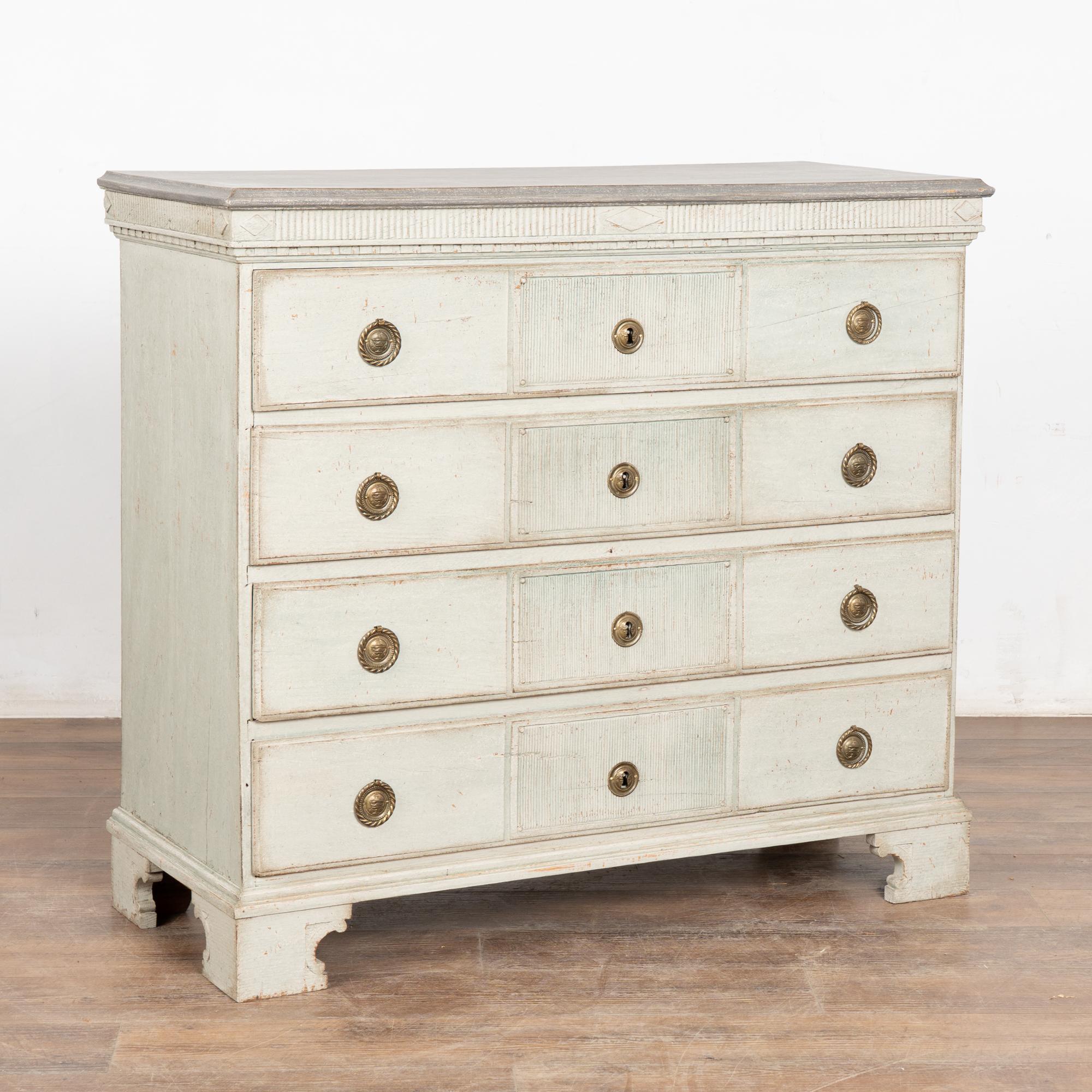 Stately Gustavian chest of four drawers with dentil molding carved along top and gentle fluted carving central to each drawer.
The newer, professionally applied light gray painted layered finish with teal undertone adds a touch of grace that fits
