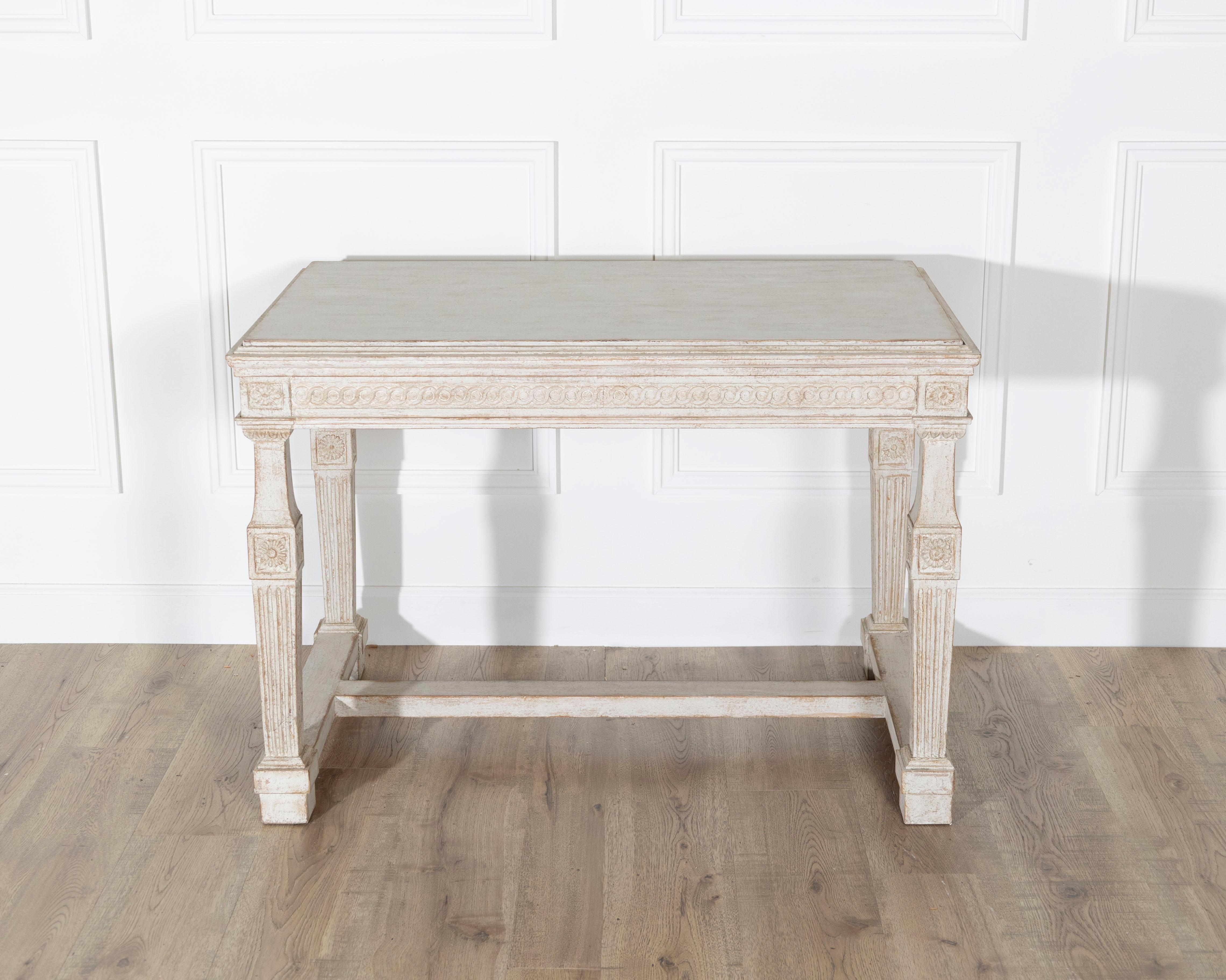 Une élégante table console gustavienne suédoise du premier quart des années 1800, fabriquée de main de maître en pin sculpté et finie dans sa peinture d'origine aux tons doux. La surface usée par le temps laisse entrevoir le bois brut sous les
