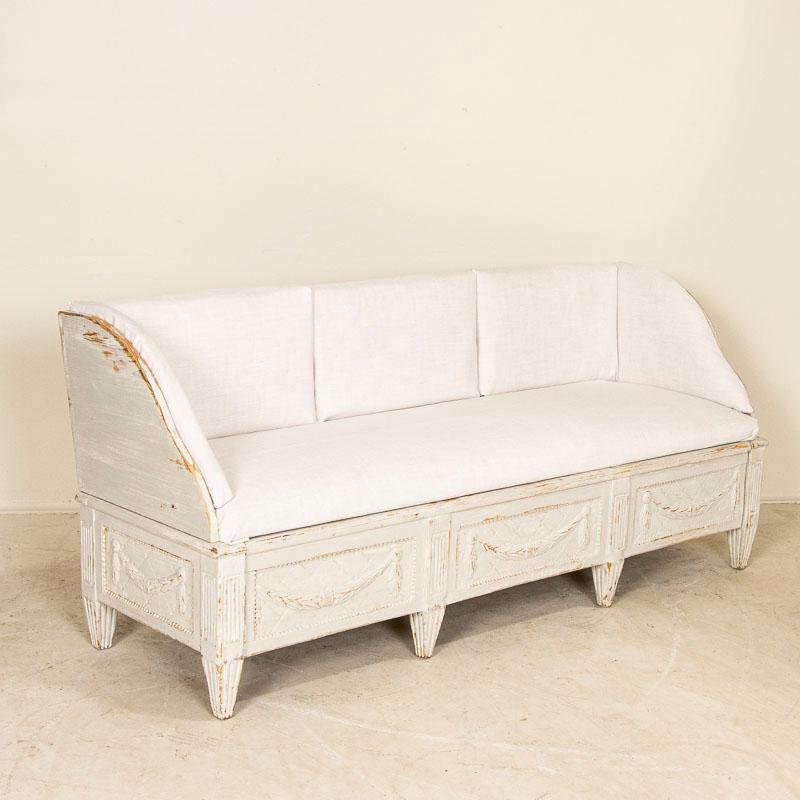 The enduring beauty of Swedish styling is timeless in this lovely gustavian settee. Note the delightful carved details include swags and tapered feet of the base. We have layed new linen fabric over the old to give buyer an idea of how simply