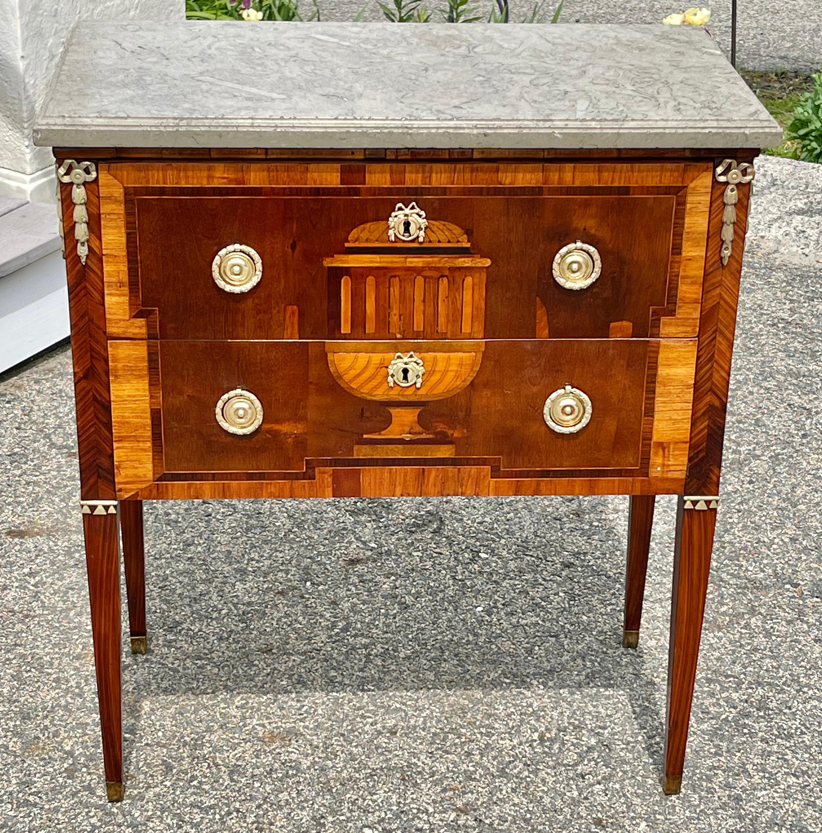 Early 19th century Swedish satinwood and fruitwood commode. Neoclassical period with original fossilized marble top. Original locks etc. Rare urn front motif with equally rare bowed laurel wreath inlays.

Exquisite.