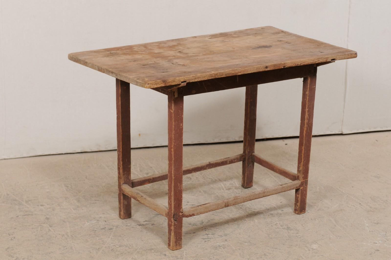 A Swedish Primitive occasional table from the early 19th century. This antique table from Sweden features a simplistic design with a rectangular-shaped top which overhangs a plain skirt. It is raised on four squared leg, supported with a straight