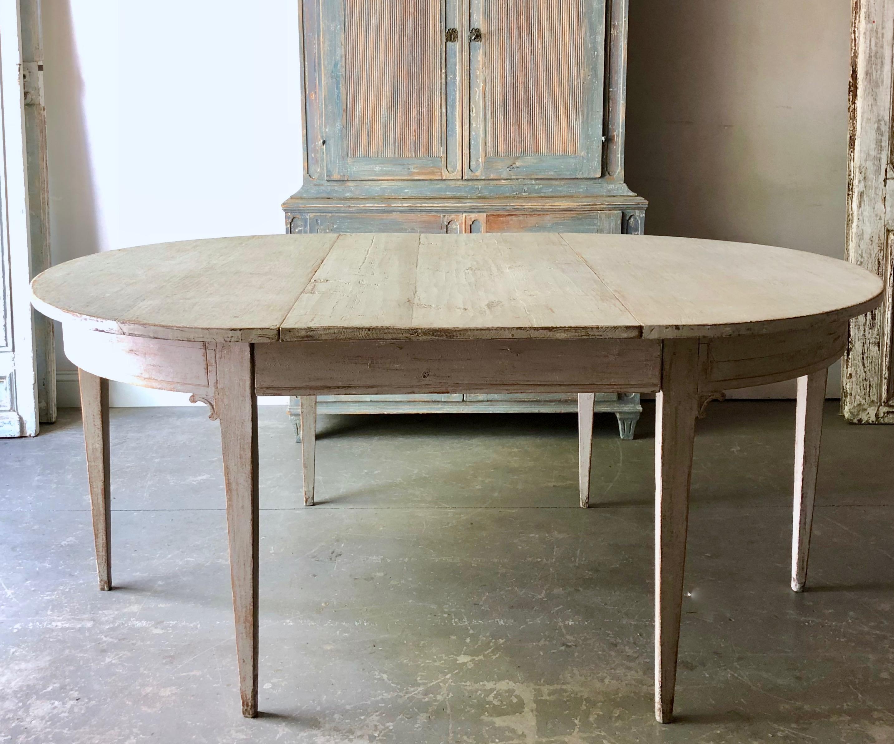 Early 19th century painted Gustavian period extending table with two leaves and tapered legs. A practical piece that can be used as round table or extended with one or two leaves up to 92