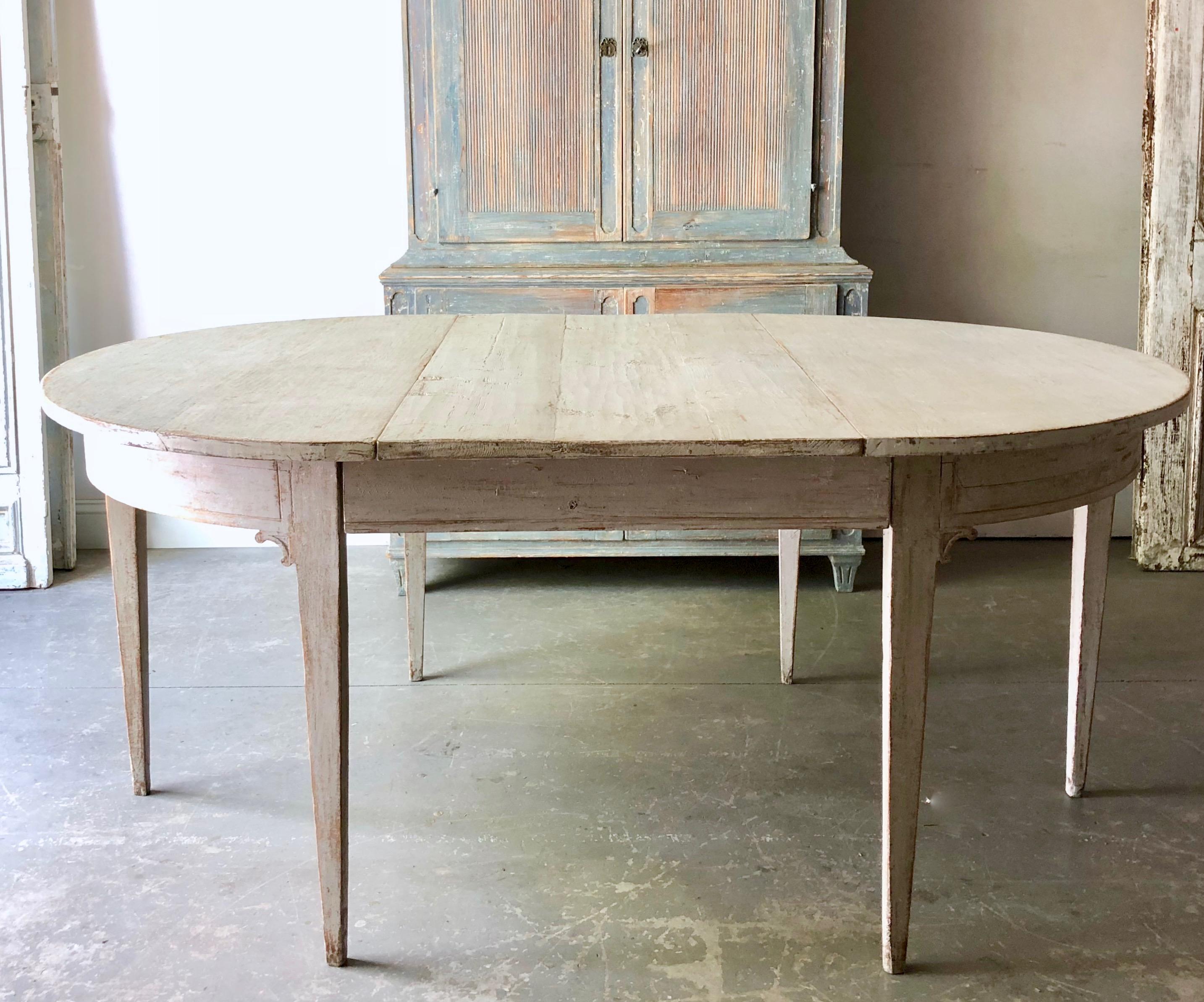 Early 19th century later painted Gustavian period extending table with two leaves and tapered legs. A practical piece that can be used as round table or extended with one or two leaves up to 92