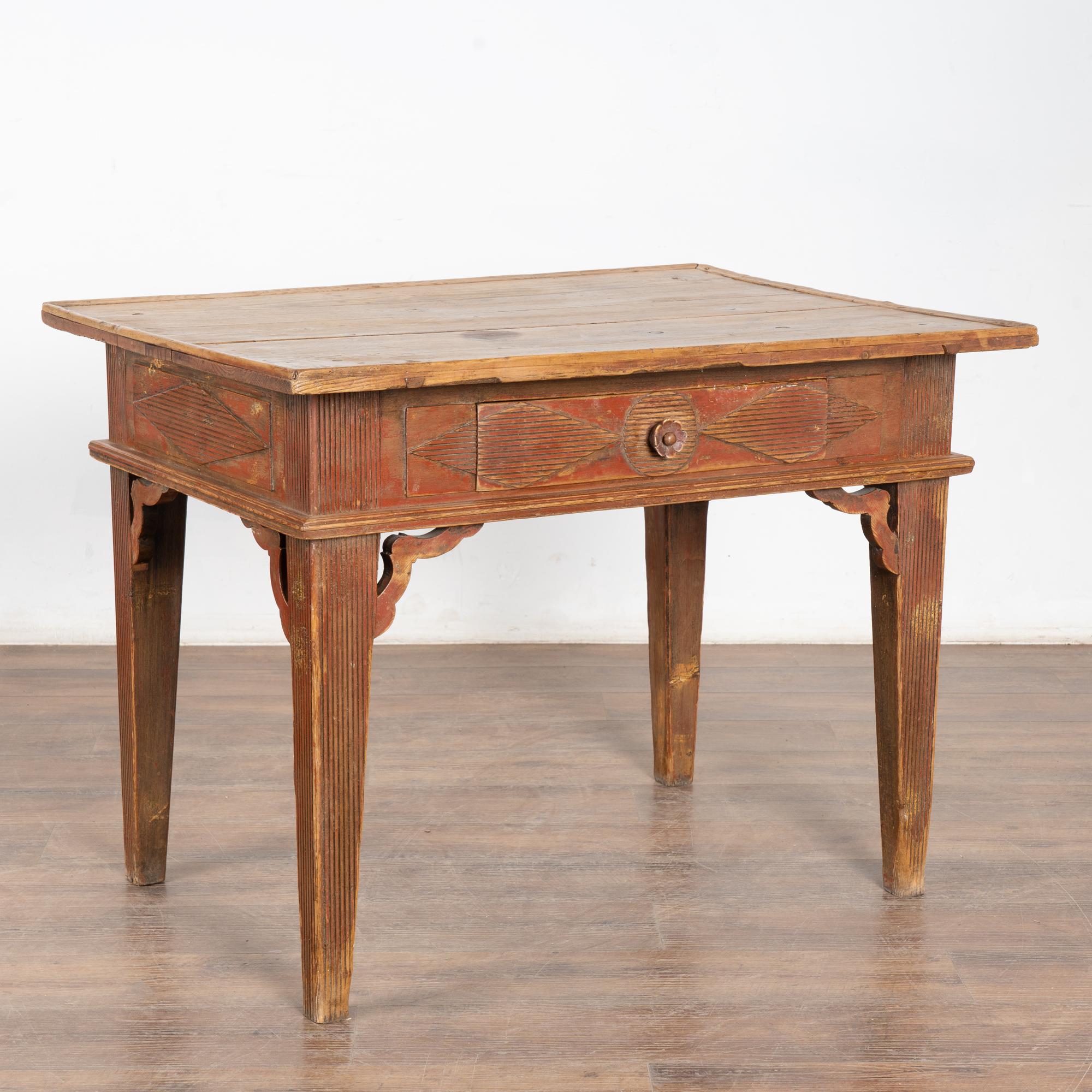 Cette charmante table d'appoint en pin provient de la campagne suédoise et conserve encore la finition originale peinte en rouge brique de la base.
Ce sont les cannelures traditionnelles le long du tiroir et des pieds, combinées à d'autres accents