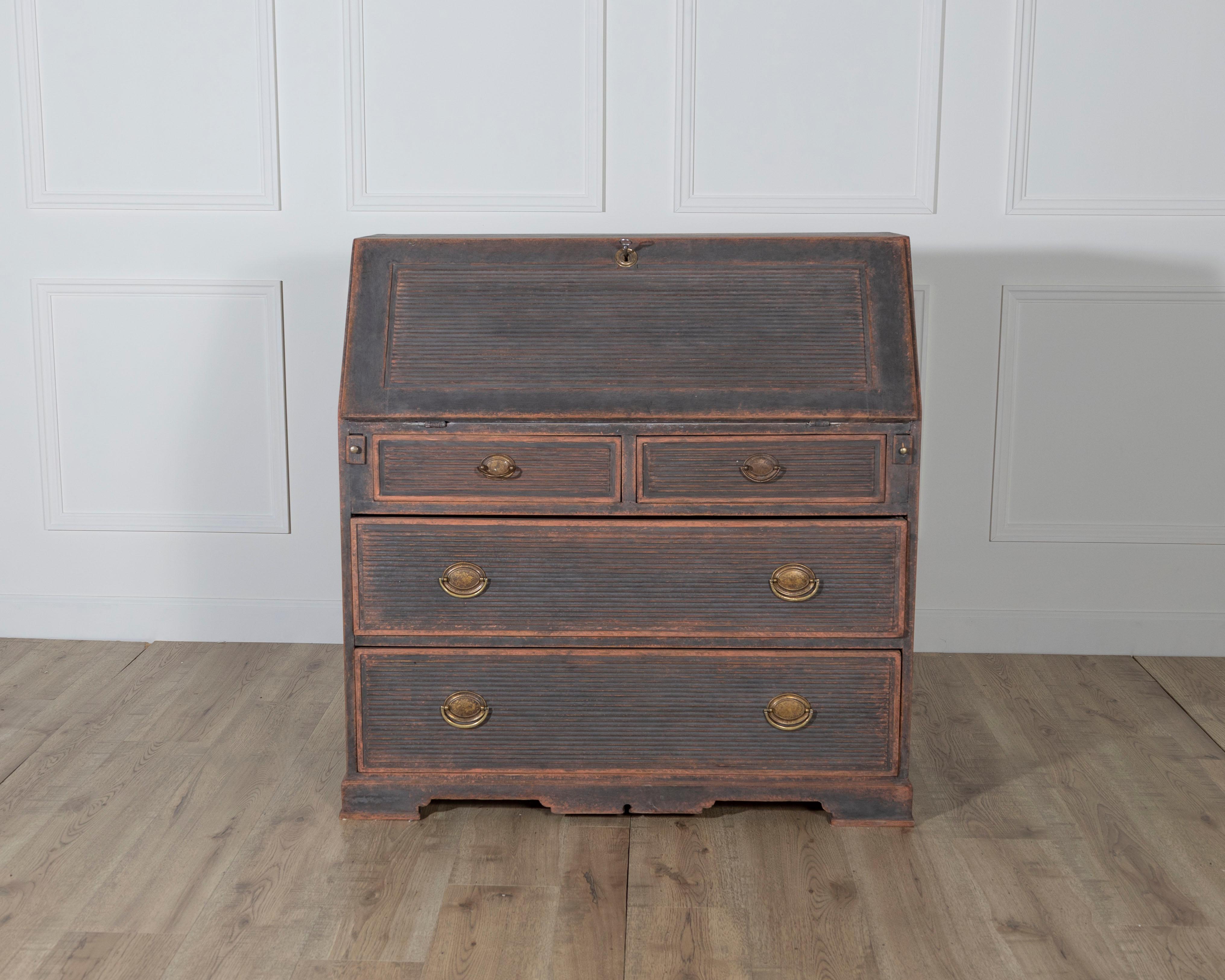A beautifully patinated Swedish secretary desk dating from circa 1810–1830, crafted in solid pine and painted in a rich, aged black. The front of the piece features decorative horizontal fluting on all drawers and the drop-front writing surface,