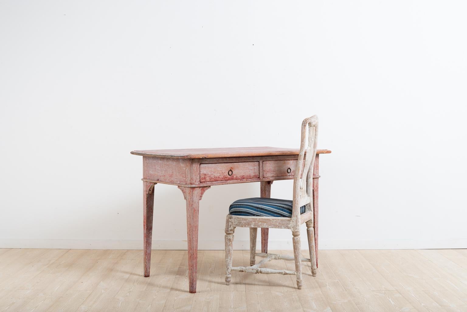 Early 19th century Swedish table. The table can both be used as a desk and side table. The table is manufactured in Gustavian Style with the characteristic straight tapered legs. Two drawers and dry scraped paint. Crafted circa 1820 in northern