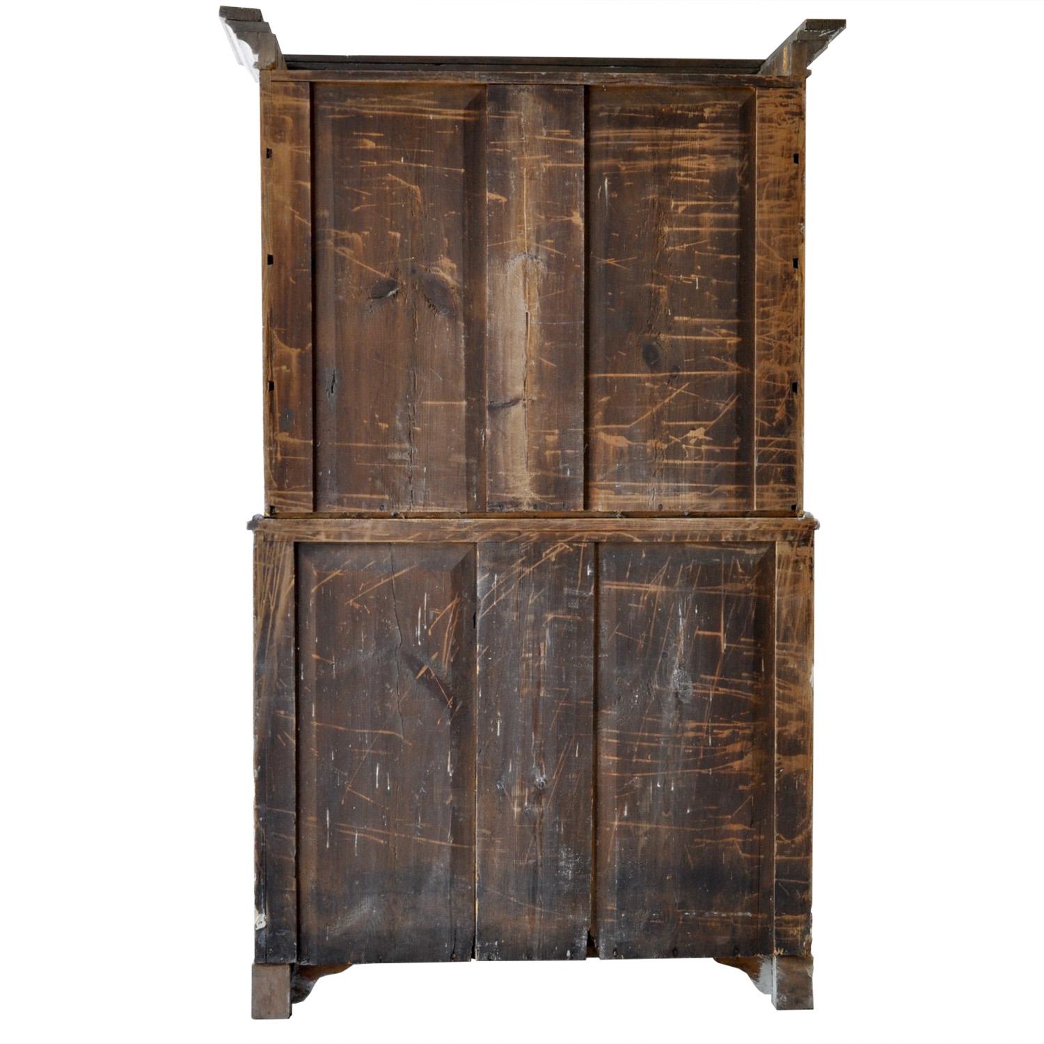 Swedish two part wood cabinet from the early 19th century. The top section features two doors with decorative Baroque carved detailing, opening to shelving. Whilst below two further doors with further detailing open to useful storage. This piece has