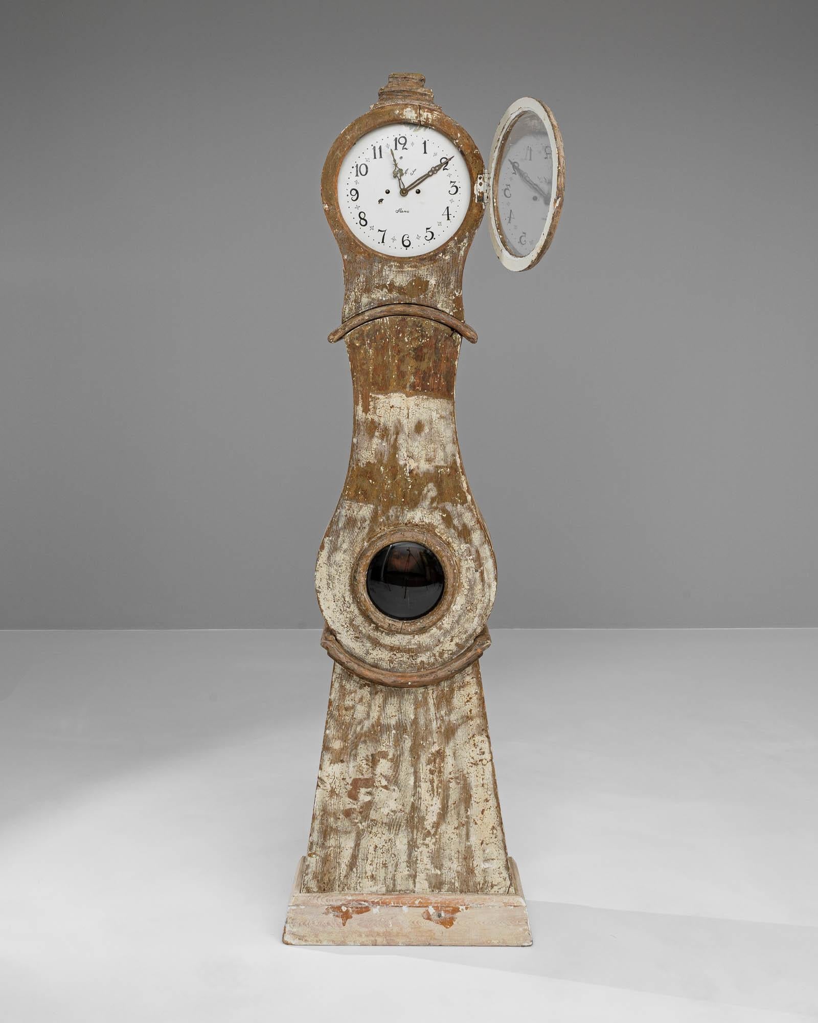 Cette horloge suédoise en bois du début du XIXe siècle, objet d'art imprégné d'un sens du temps et de la tradition, évoque les chuchotements de l'histoire. Sa présence majestueuse est accentuée par le charme rustique du bois usé par les intempéries,