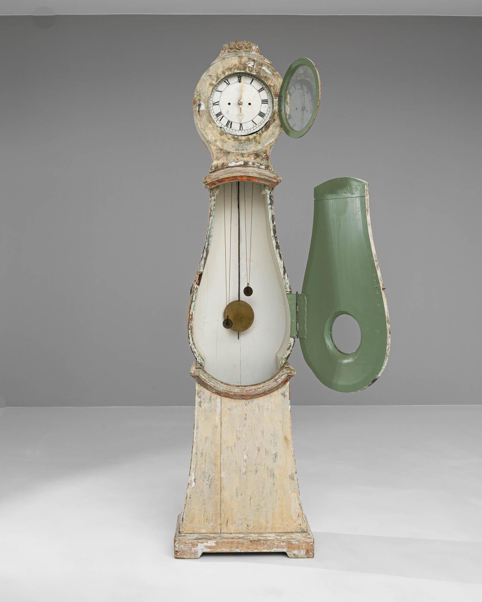 This early 19th Century Swedish wooden floor clock stands as an enduring icon of antique elegance and craftsmanship. The clock boasts a body painted in a delicate, faded hue, reminiscent of the patina that gracefully forms over time, giving it a