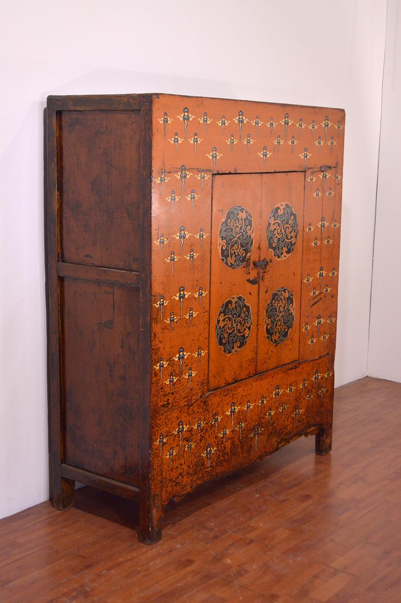 A 19th century Tibetan cabinet from Kham province, east Tibet. The cabinet with its two doors features a central circolar painting surrounded by cloud pattern painting. A beautiful textile inspired pattern surrounds the central painting on a orange