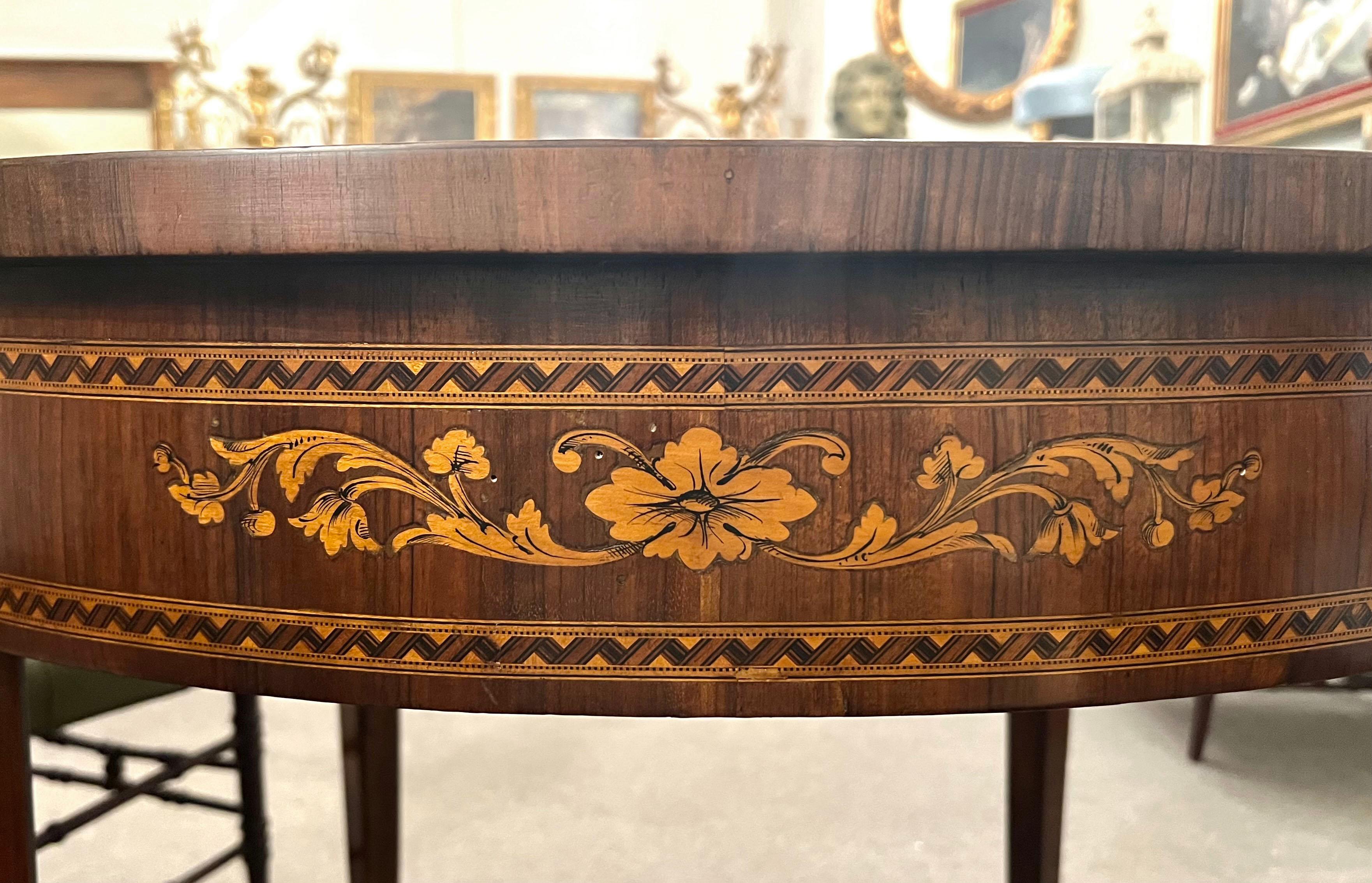 Elegant circular coffee table entirely veneered in walnut and finely inlaid with floral and vegetal motifs in fruit wood. The inlays decorate the top, the band and the legs of the coffee table in a refined way, with details such as framed bands,