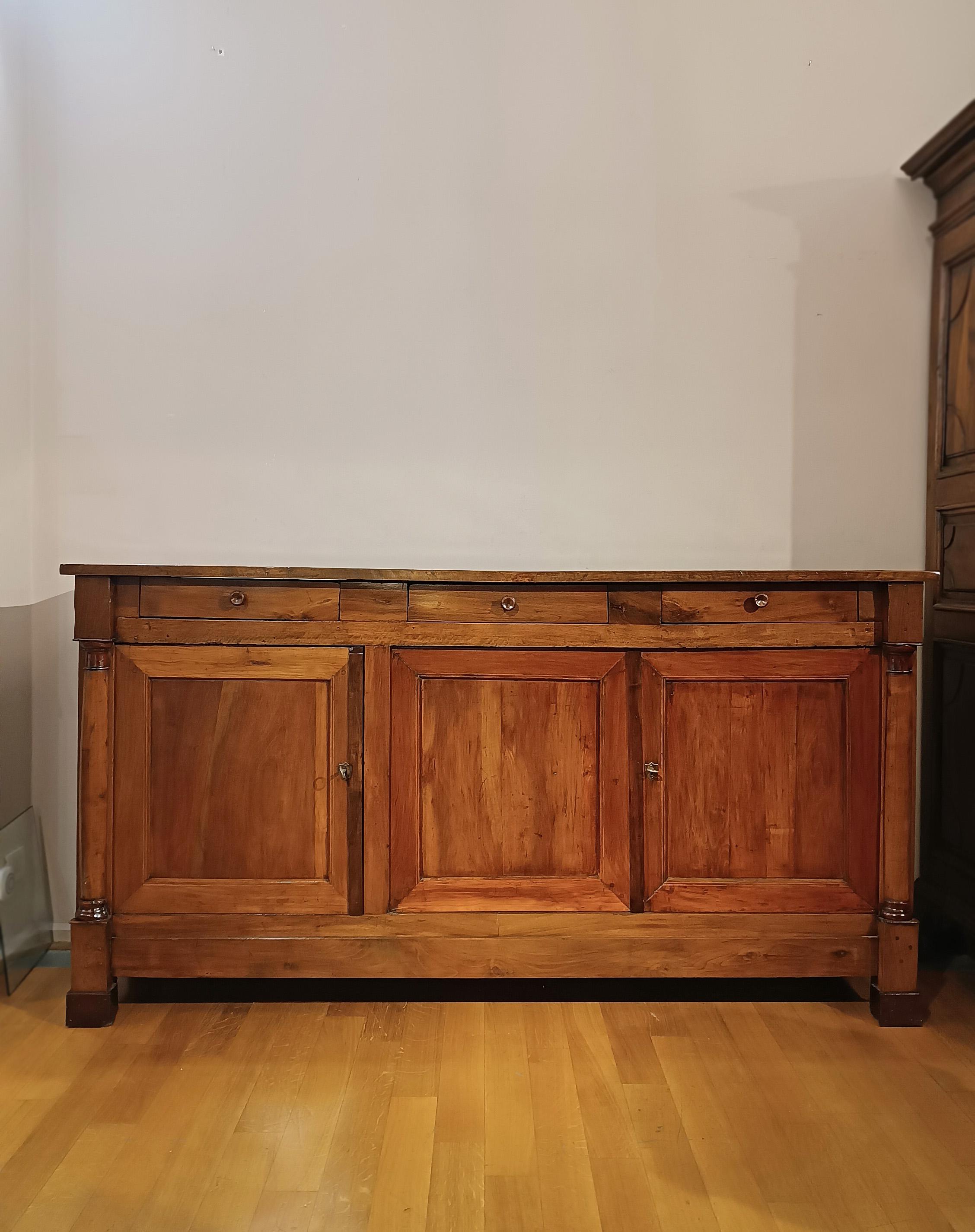 Elegant sideboard in solid walnut, finely carved. This generously sized sideboard has three drawers positioned under the top and two front doors that open onto two practical shelves, ideal for storing objects. Its elegance is expressed in the
