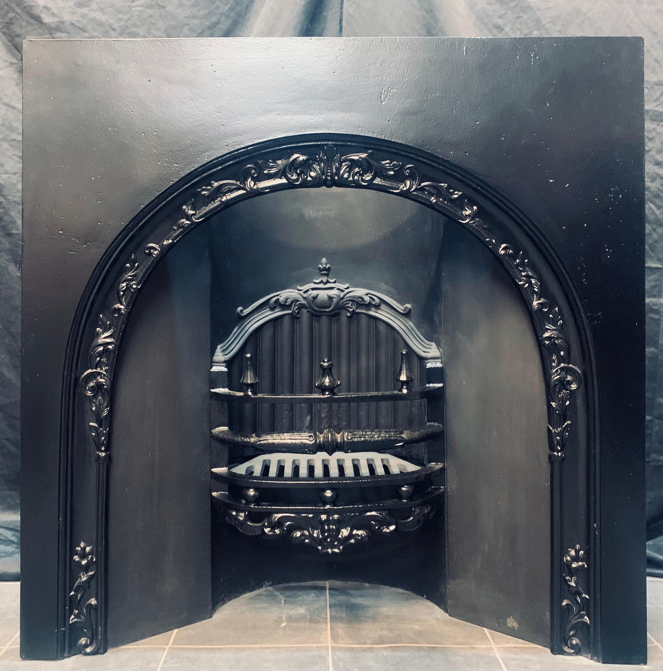 An early Victorian 19th century cast iron fireplace insert with an arched opening, showing high relief casting to the arch, a three barred curved fire front with cushion spacers and topped by finials, a curved and reeded fire back, probably by