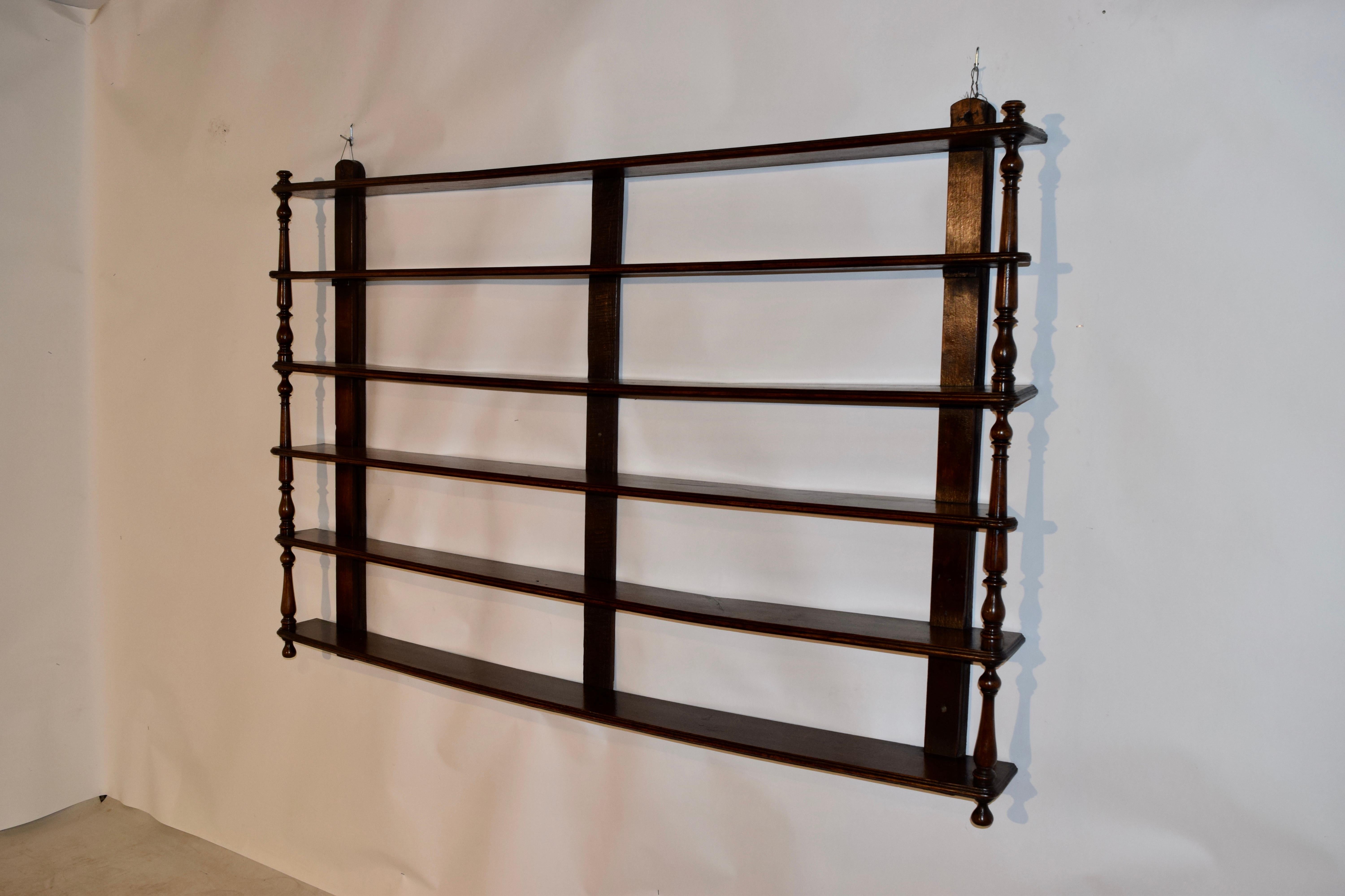 Early 19th century oak wall shelf from England. there are three wall braces on the back which have six shelves with molded edges attached to them and they are joined on the front by hand turned shelf supports. Finished with hand turned finials on