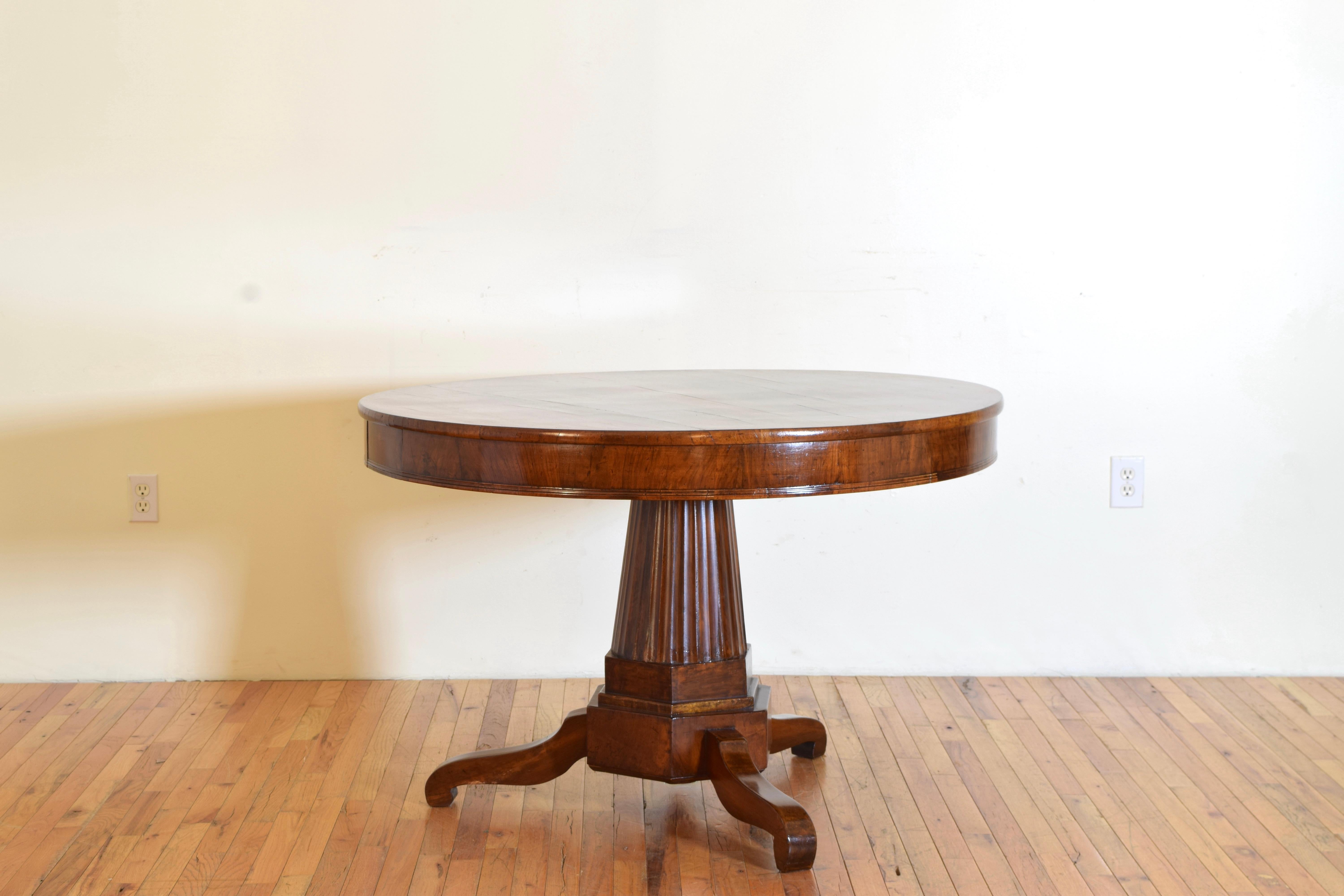 Having a circular top with an apron housing two opposite drawers over a bold fluted and tapering pedestal atop a hexagonal base raised on three carved legs. The walnut is solid with a wonderful patina.