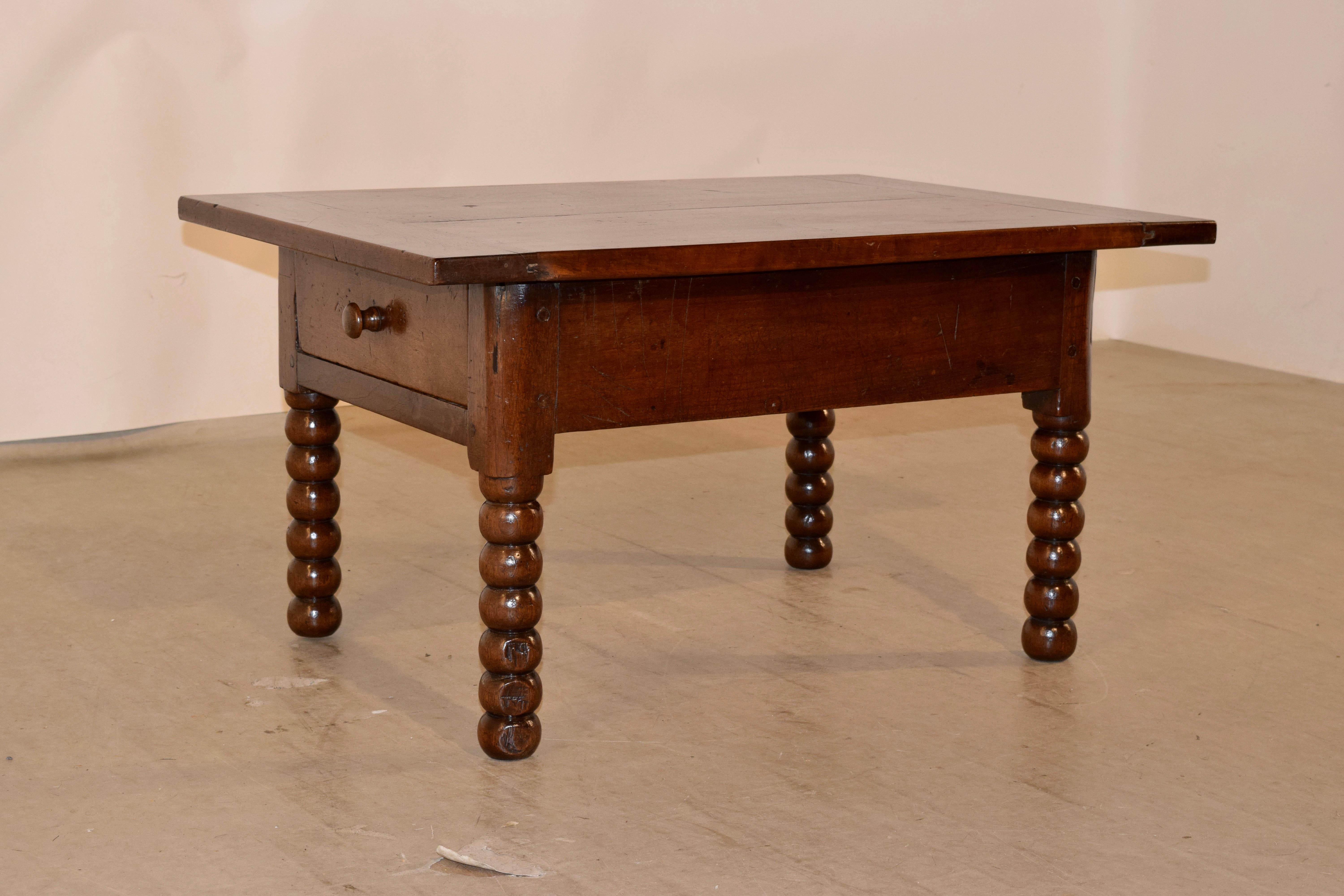 Early 19th century walnut coffee table from France. The top is made from two thick boards and has banded ends, following down to a simple apron, which contains a single drawer and is raised on hand-turned bobbin legs.