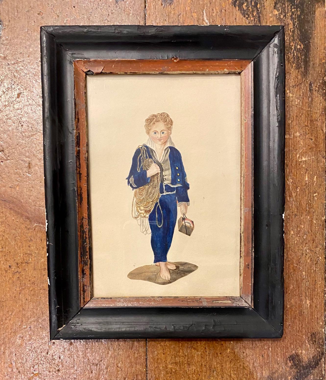 Early 19th century watercolor of a Sailor Boy, a very unusual watercolor on thick paper or card, precisely cut-out and mounted on a background paper. The blond curly haired and blue eyed lad wears a rich blue midshipman's suit, holding a boxed