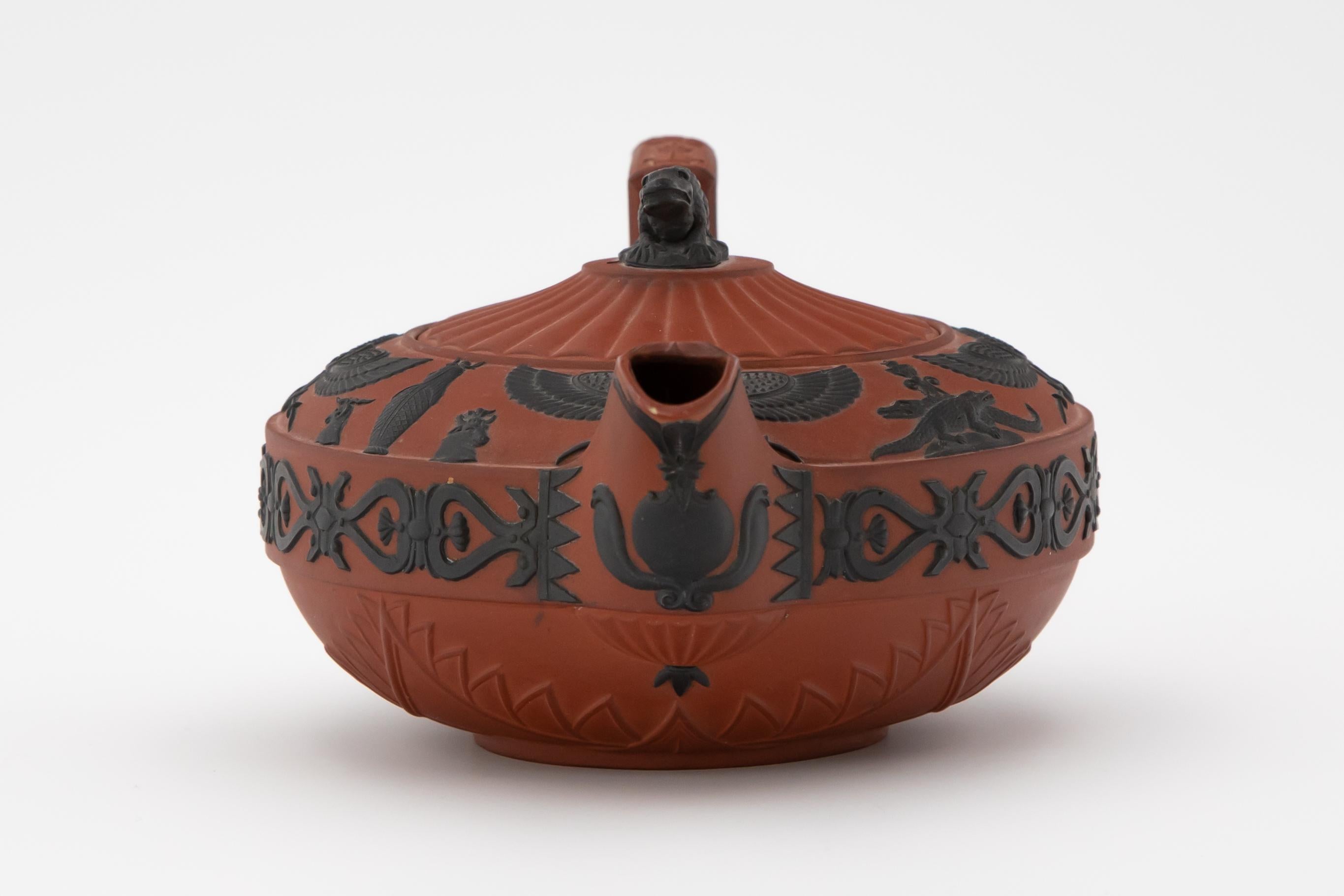 A rosso antico teapot made by Wedgwood ca. 1810. The pot's red body is accentuated by black basalt details in the Egyptian Revival style.

This rosso antico teapot is a fine example of the Egyptian Revival style, popularized in Europe during