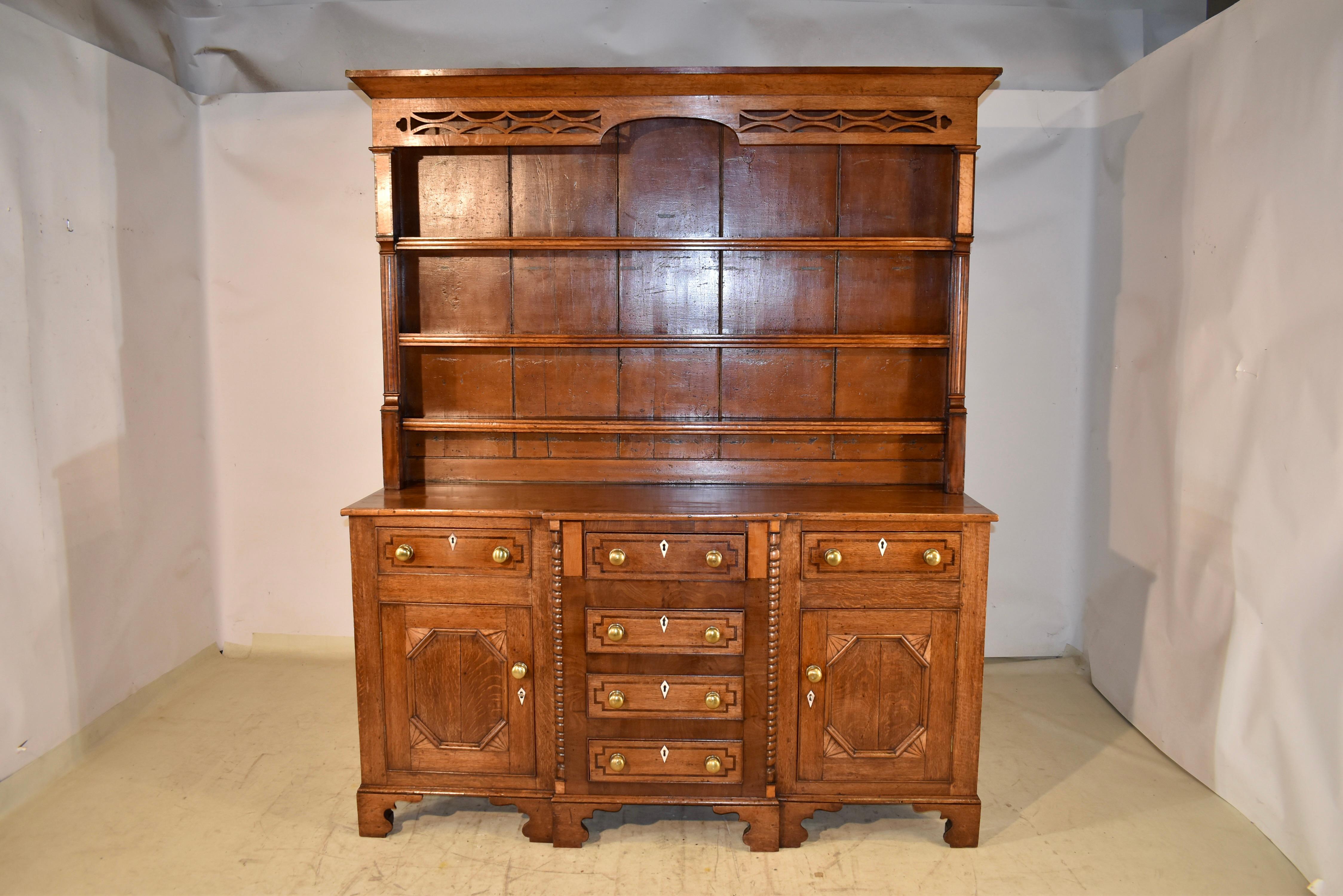 Comò in quercia gallese intarsiato dell'inizio del XIX secolo. La cassettiera ha un'incantevole e semplice corona su un meraviglioso piano con un design traforato e smerlato. Il piano presenta tre ripiani, tutti con frontali modanati, affiancati da