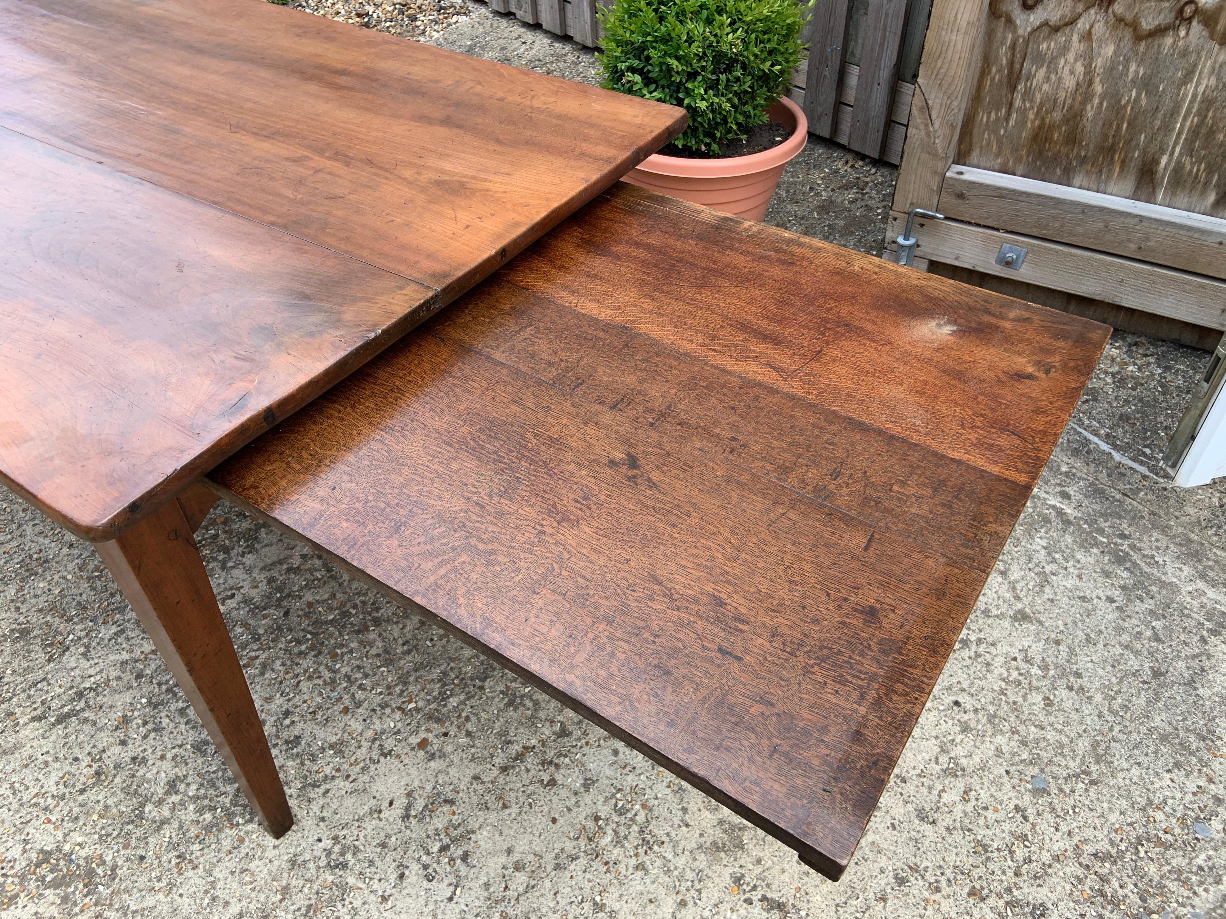 Early 19th century wide cherry farmhouse table with slide and tapered legs. Table has a three plank top which sits on a sturdy cherry base. Beautiful color and patination.