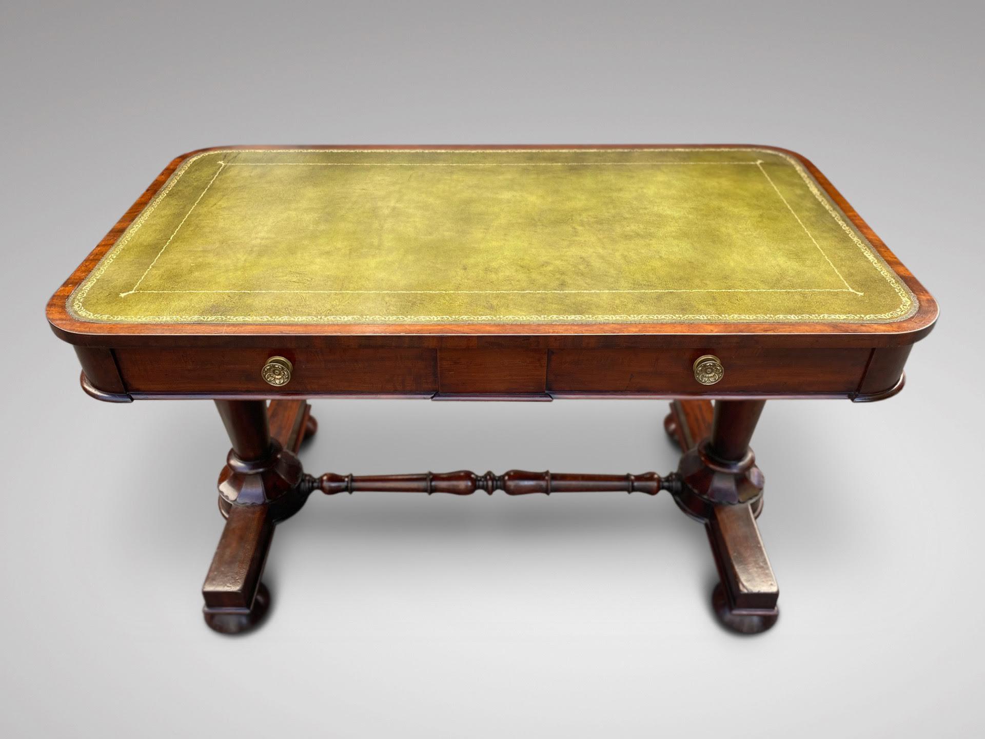 A 19th century, William IV period mahogany library writing table. Rectangular green tooled leather top above frieze with geometric moulding to the centre, comprising two drawers with brass circular handles, all standing on twin octagonal tapered