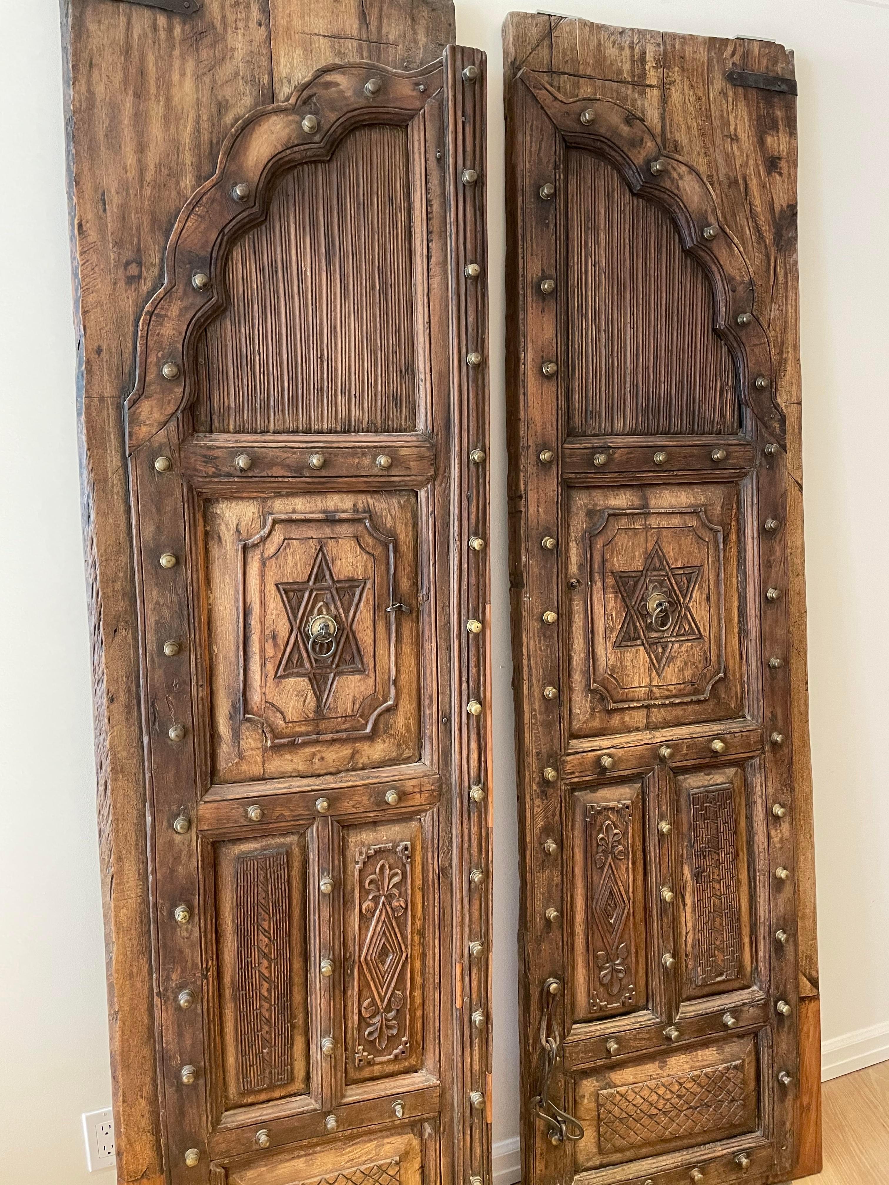 The intricate detail carving work decorating this ornate Indian temple door makes it a unique collector’s item. The wood frame is delicately carved with rows of individually turned pieces of wood accenting the transom. This unique teak door from