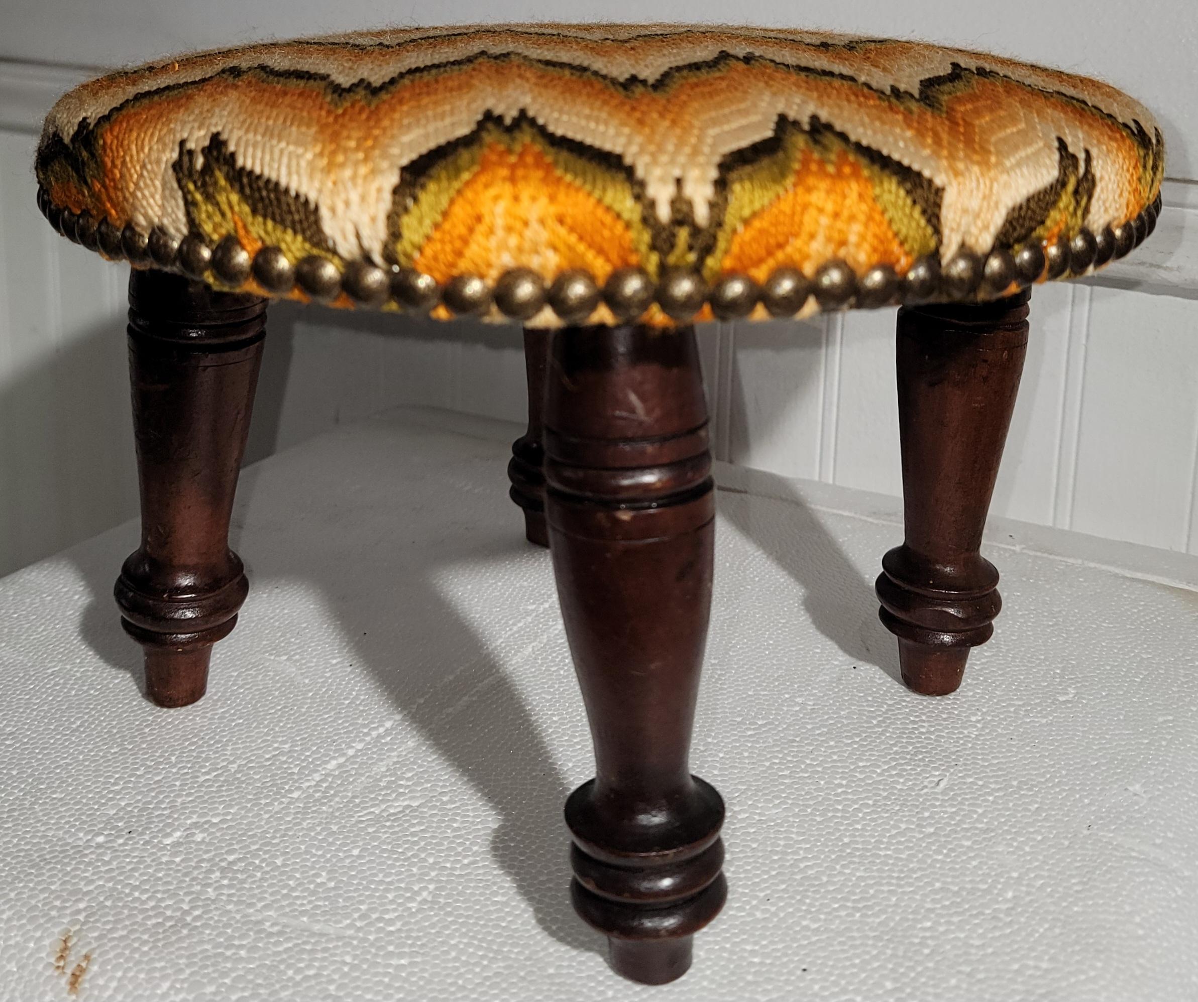 This fantastic hand carved foot stool is dated 1842 and is made in New Hampshire.The condition is pristine.The flame stitch wool fabric was newly re-upholstered and is also in very good condition.