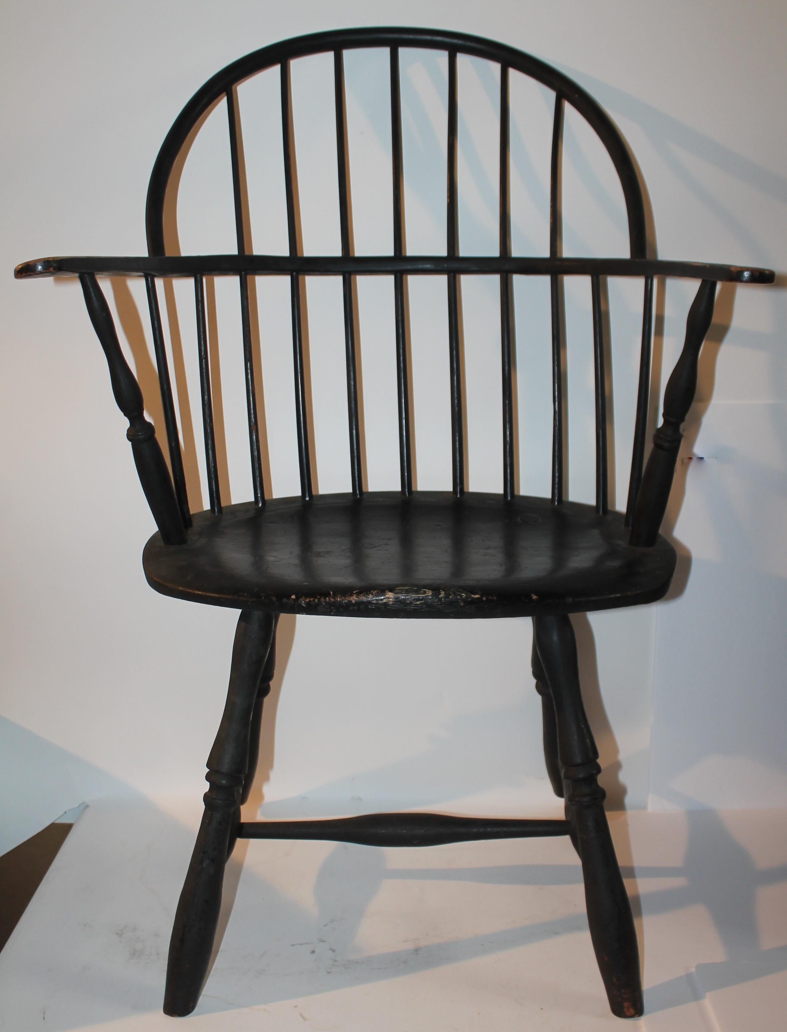 Cette chaise Windsor de Nouvelle-Angleterre à dossier arrondi et à accoudoirs allongés est en excellent état. La surface peinte en noir est entièrement d'origine et présente une magnifique patine vieillie. Le dossier de la canne à pêche est visible