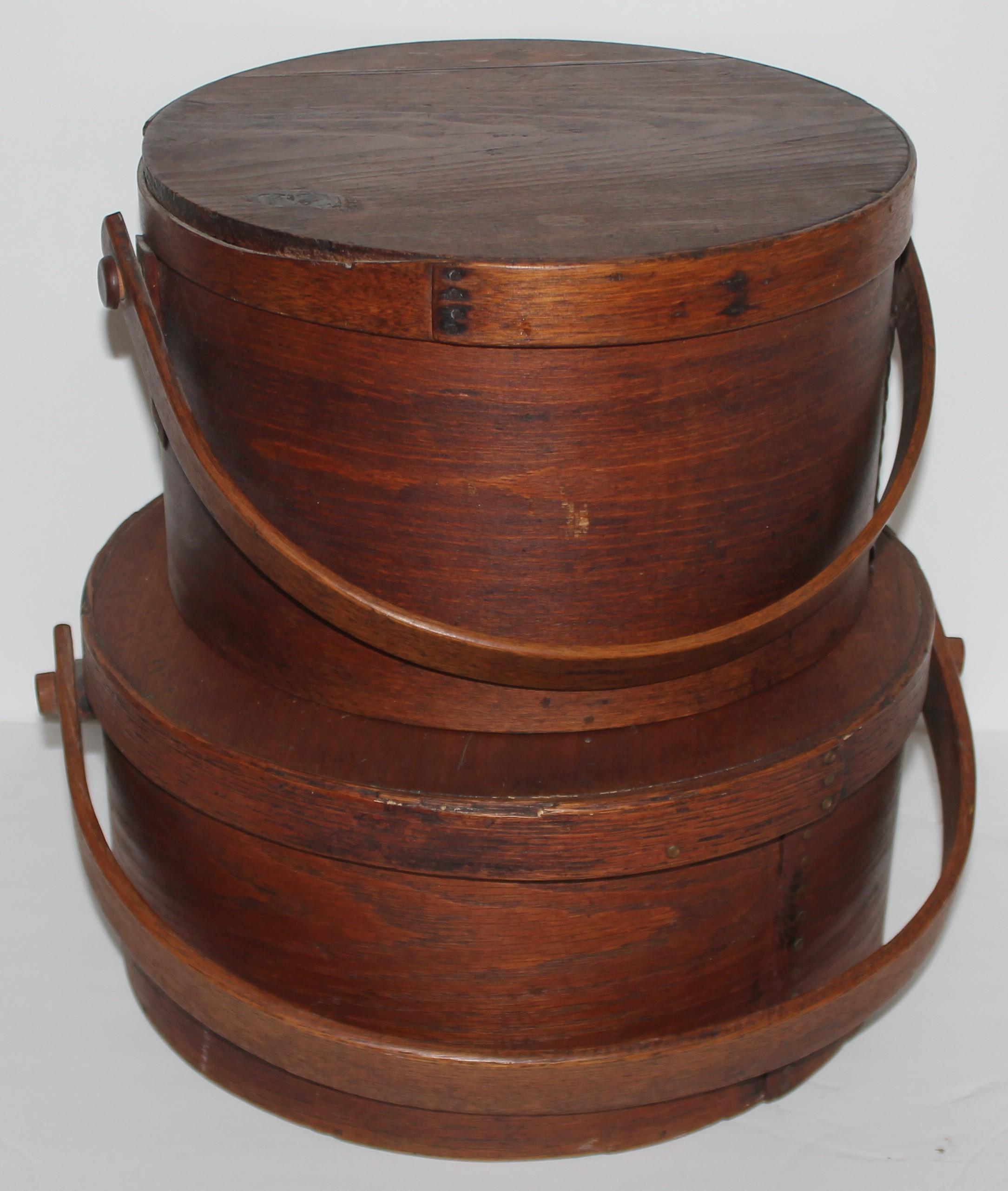 These fine early hand crafted bail handled pantry boxes are in great condition. There is minor wear of the edge of the top of the smaller pantry but is still tight and sturdy. Sold as a pair. Small : ( 7 W x 11.5 D ) Large : ( 7 high x 13 diameter ).