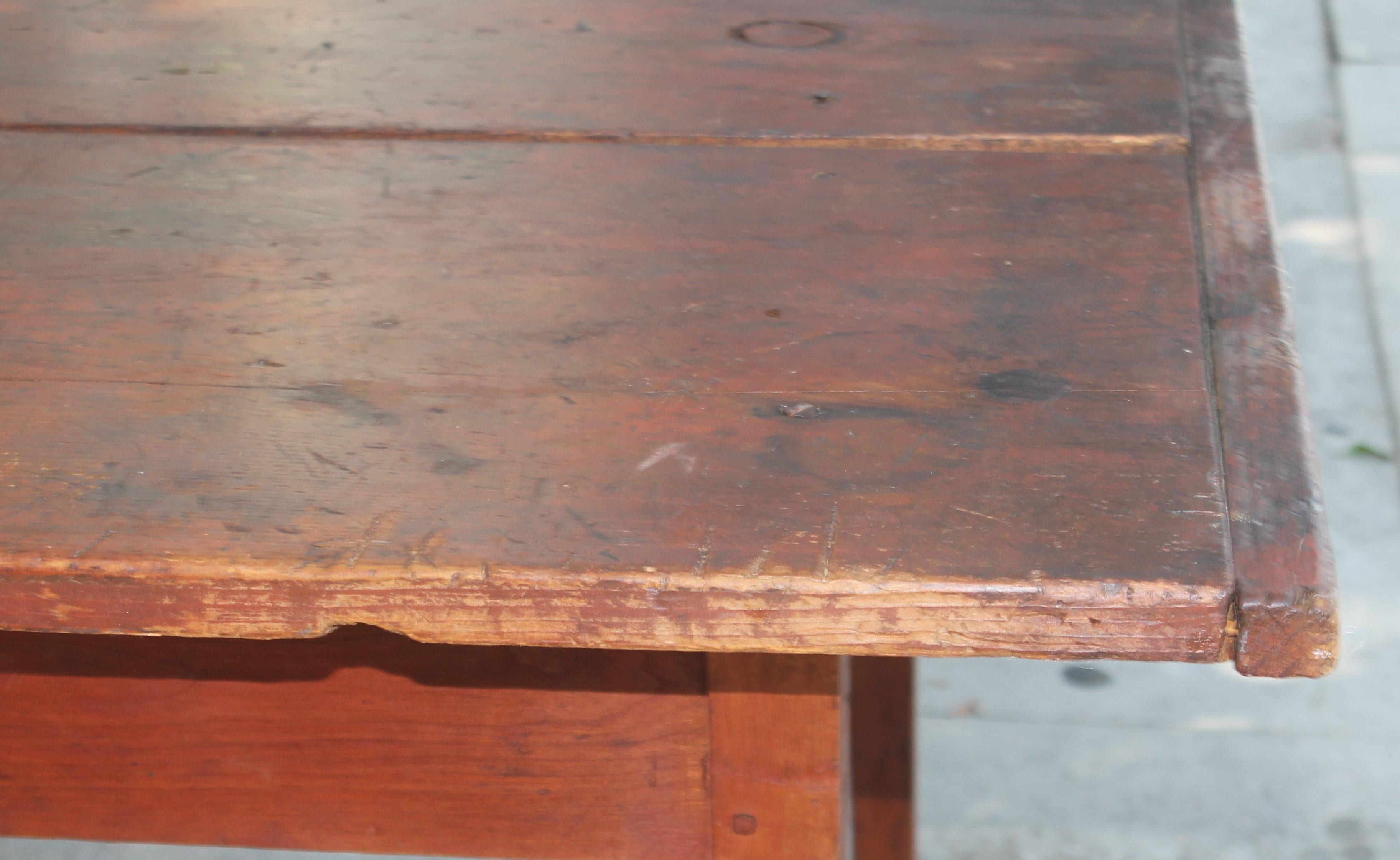 Early 19thc original red painted farm table from Pennsylvania in very good sturdy condition. The taper legs are amazing and two board top. There are four early hand made screws from the early 1800's in the top of the table. Probably put in years