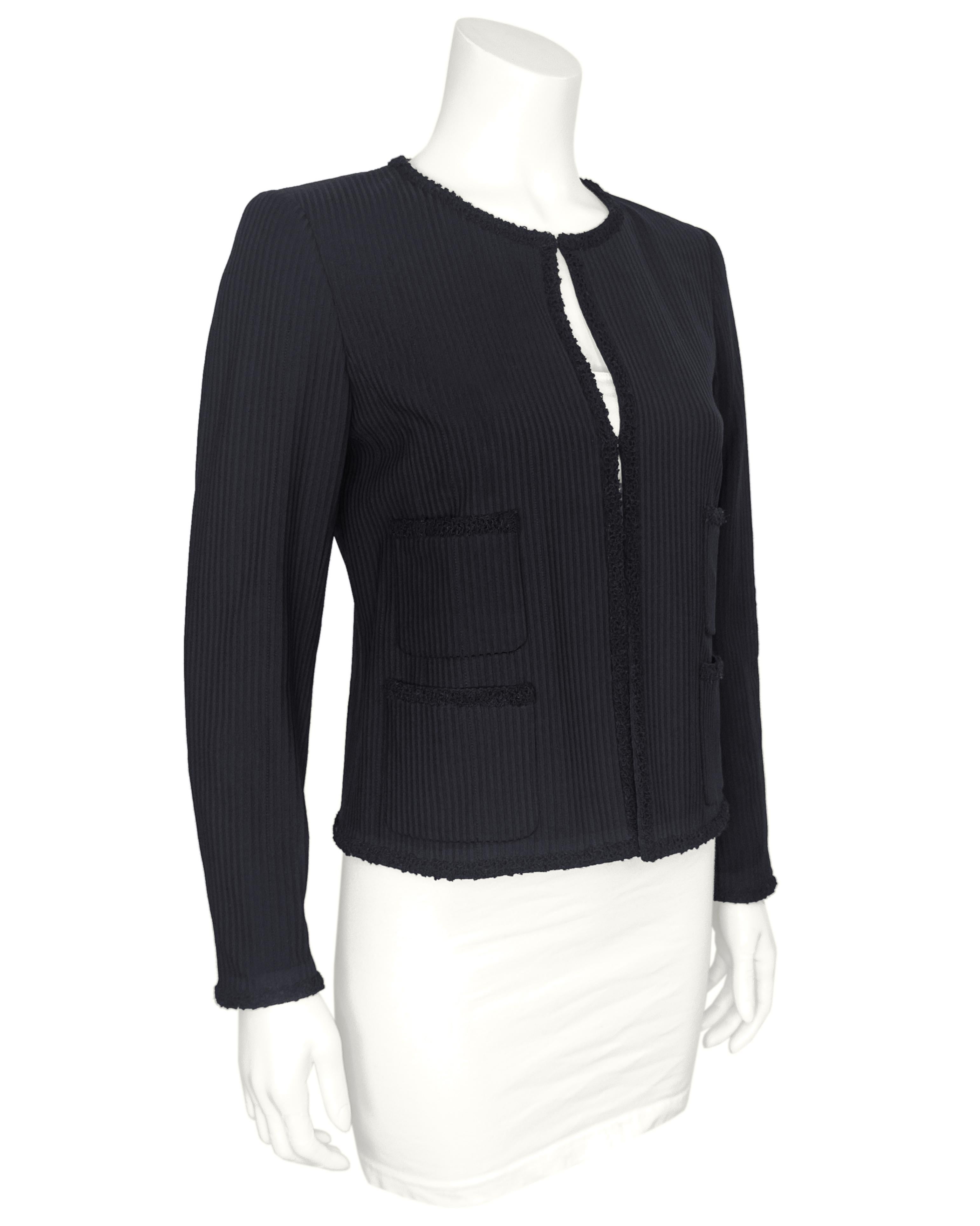 Veste Chanel élégamment raffinée du début des années 2000. Cette veste présente une silhouette sans col avec des épaules légèrement paddées et une coupe ajustée. Des rayures verticales côtelées ton sur ton noires allongent le cadre, tandis que des