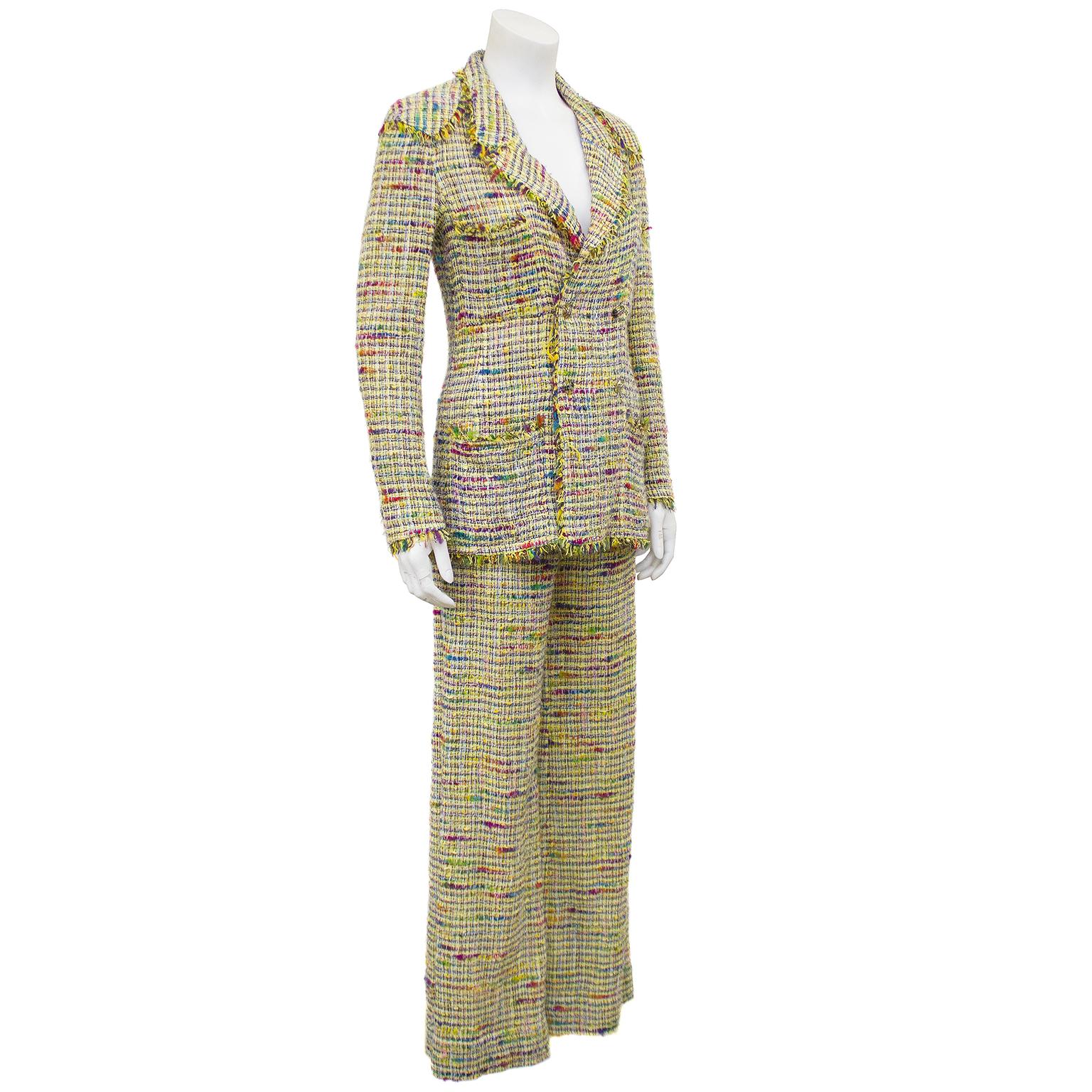 Early 2000s Chanel yellow and red boucle pants suit. The double breasted jacket has fringe along the lapel, epaulettes, pockets, front, hem and cuffs. The buttons are clear plexi discs with colored thread and silver CCs. Four front patch pockets;
