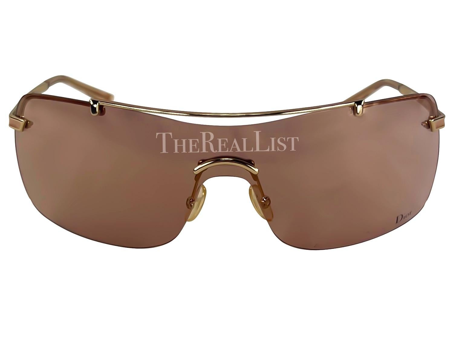 Presenting a pair of dusty pink Christian Dior by John Galliano sunglasses. From the early 2000s, these rimless shield sunglasses showcase exquisite craftsmanship. The gold-tone hardware adds a touch of opulence, while the thin arms, adorned with a