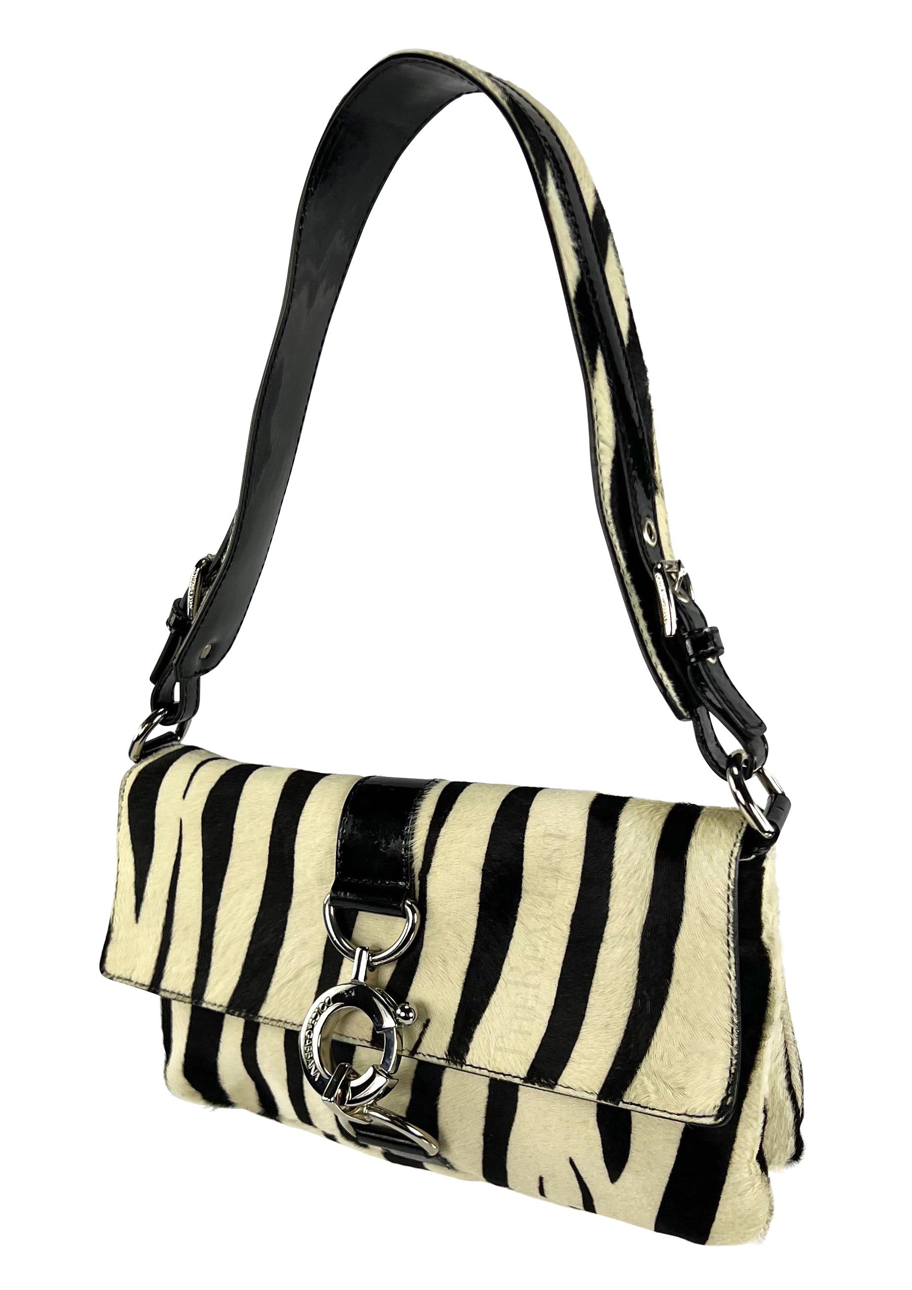 This Dolce & Gabbana shoulder bag from the early 2000s features a striking black and white zebra print on pony hair. It’s accented with silver-tone hardware and patent leather, offering a blend of style and practicality.

Approximate