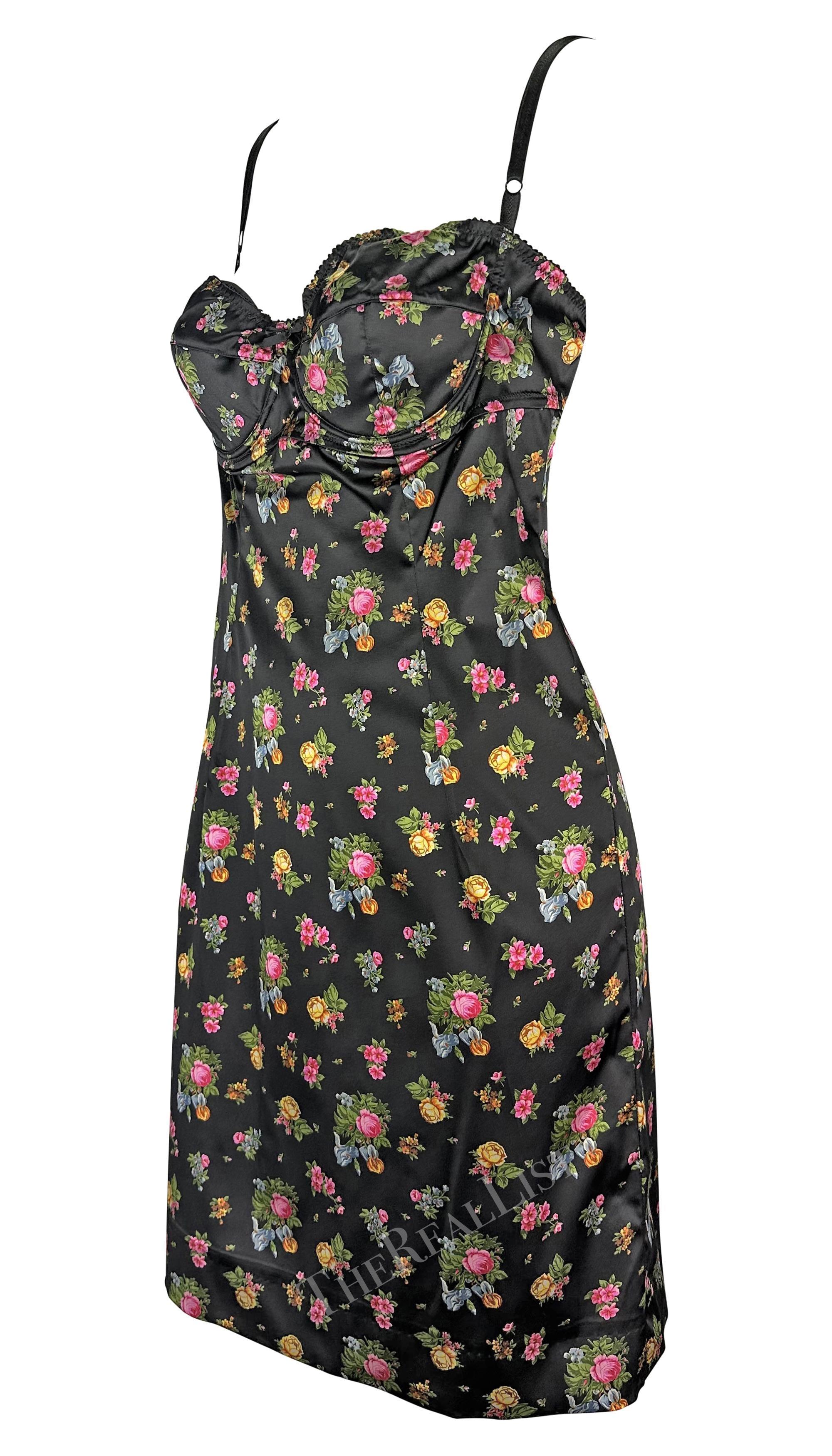 Présentation d'une fabuleuse mini robe Dolce & Gabbana à fleurs noires. Datant du début des années 2000, cette robe noire ajustée présente un imprimé de roses multicolores. La robe est complétée par un buste souligné qui donne un effet lingerie et