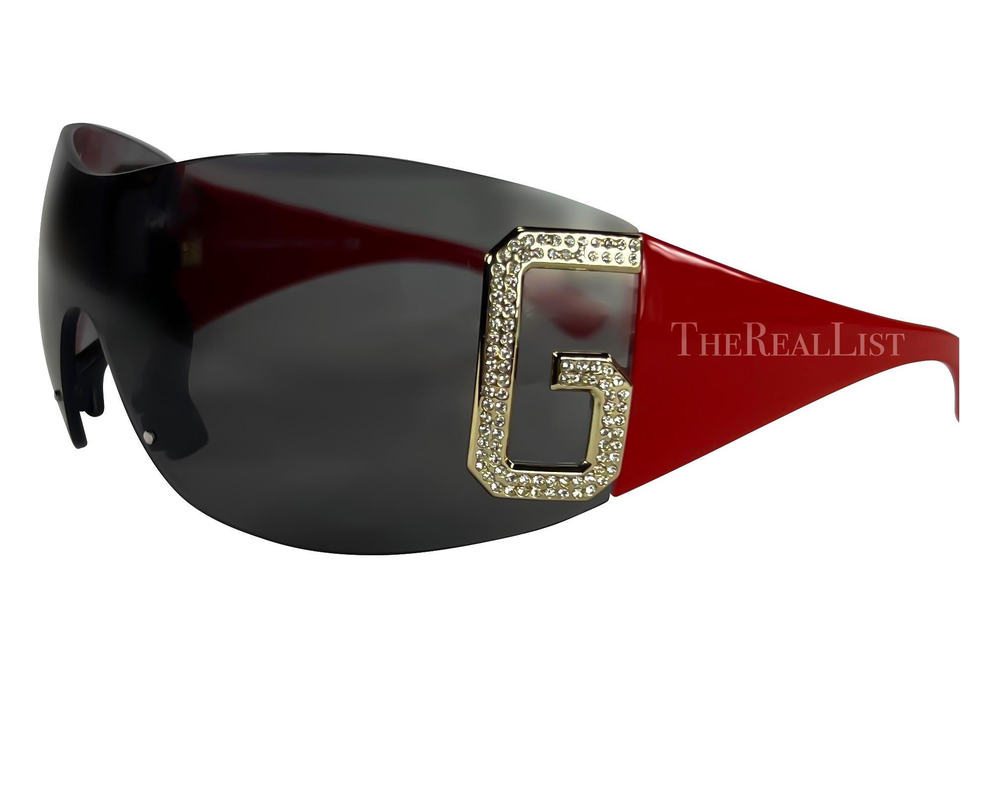 Ich präsentiere eine rote Sonnenbrille von Dolce & Gabbana. Diese übergroße, randlose Sonnenbrille aus den frühen 2000er Jahren strahlt Kühnheit und Selbstbewusstsein aus. Die großen, silberfarbenen, strassbesetzten Logos 