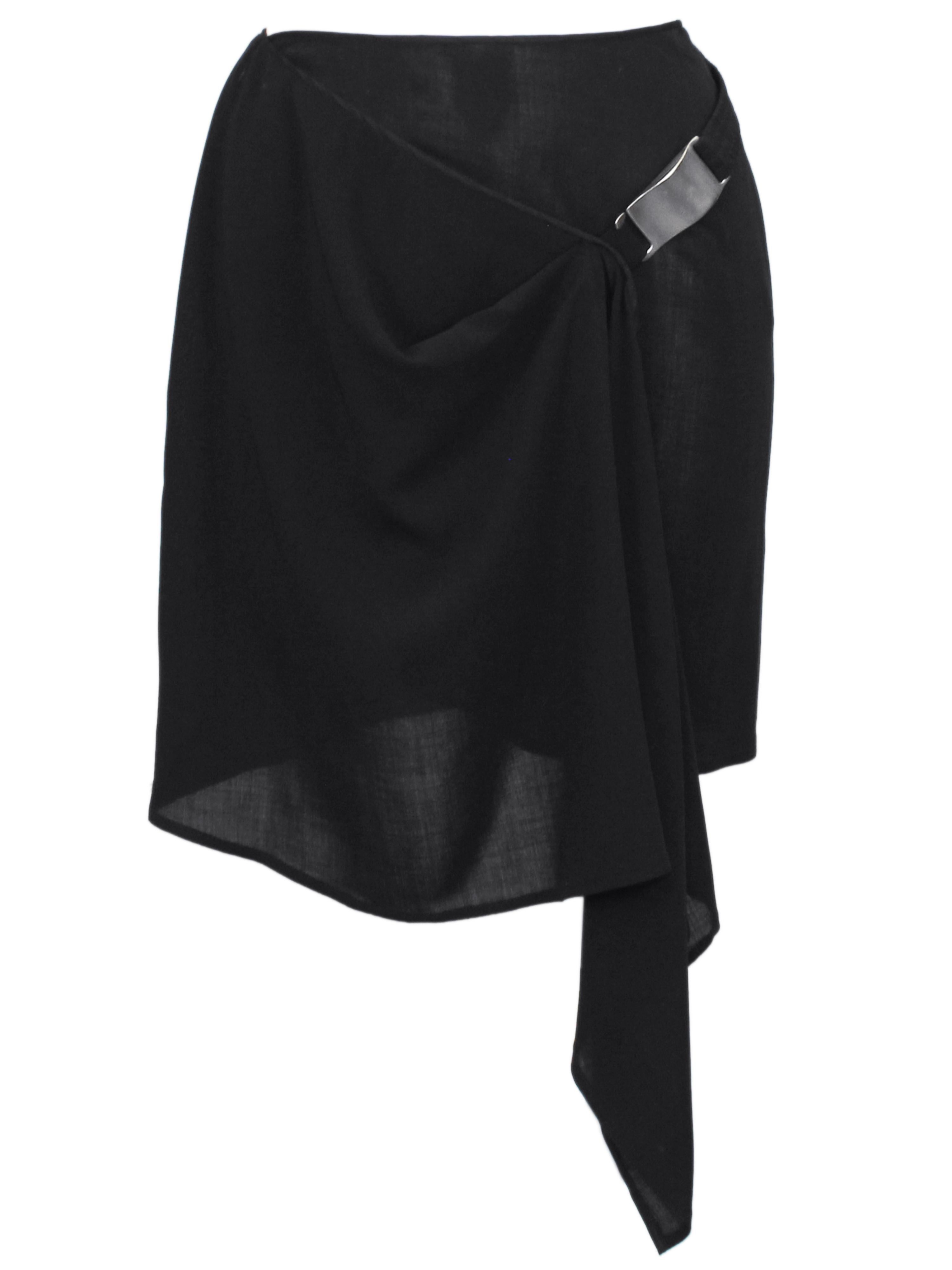 Donna Karan thin semi sheer black wool crepe mini skirt from the early 2000s. The skirt wraps and has an elasticized belt that wraps around the body with a matte silver metal large modern buckle/hook that fastens to a fabric loop. The skirt drapes