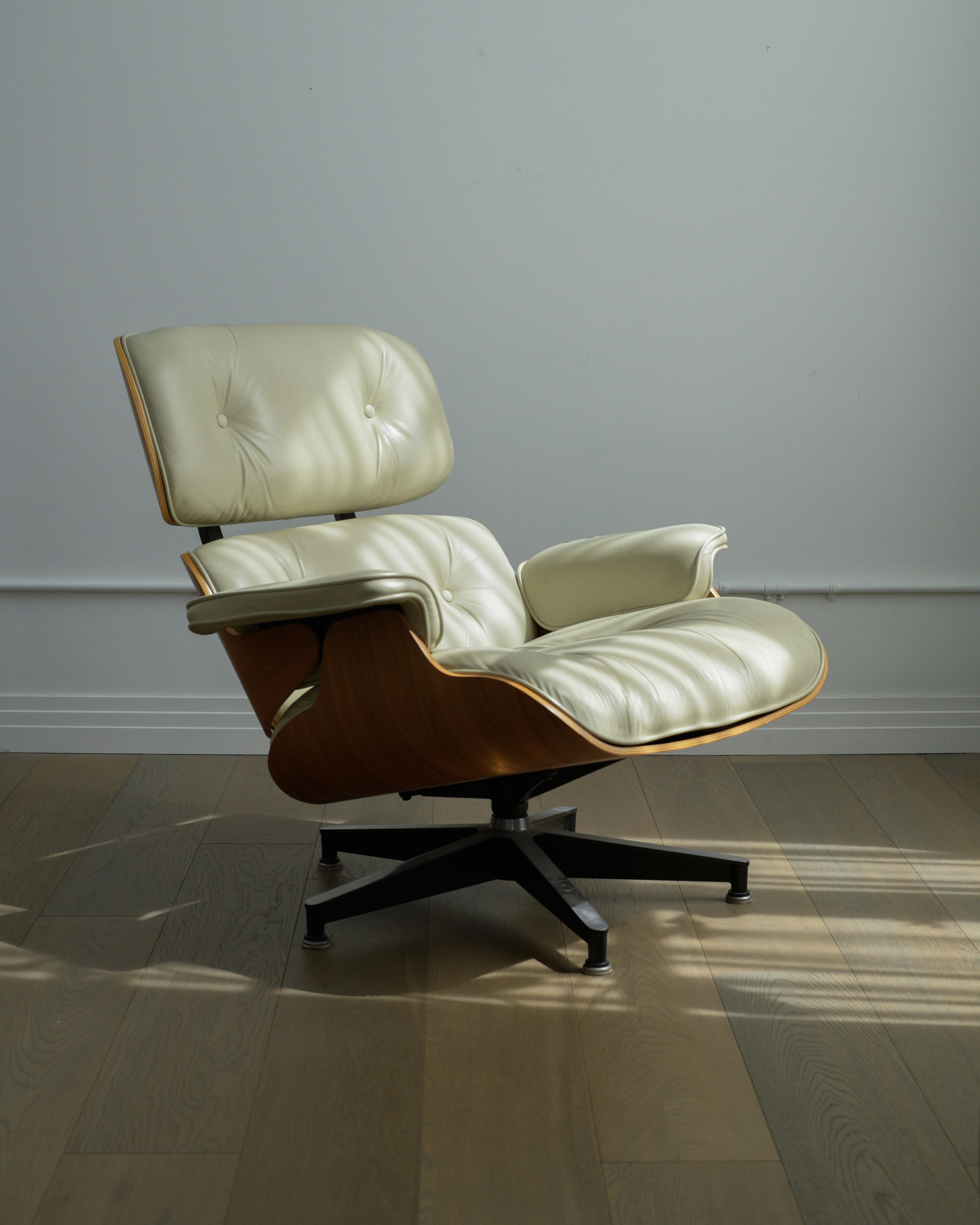 Una preciosa Silla Eames Lounge y Otomana de Herman Miller en piel blanca. 

Tanto la silla como la otomana están en buen estado, con una bonita pátina desgastada en el cuero. Hay algunas pequeñas abrasiones dispersas en la cáscara de nogal, pero en