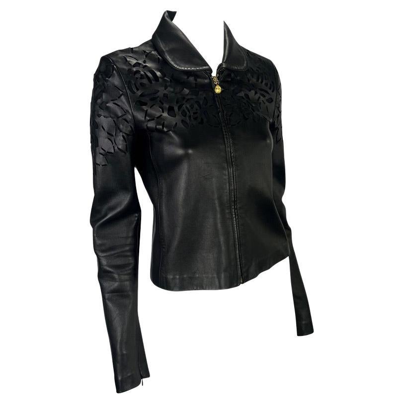 Presenting a sleek black Gianni Versace leather jacket designed by Donatella Versace. This collared leather jacket features a flat, rounded collar, cut floral design, and Medusa logo zipper pulls. The unique floral cut-out details on the coat have a