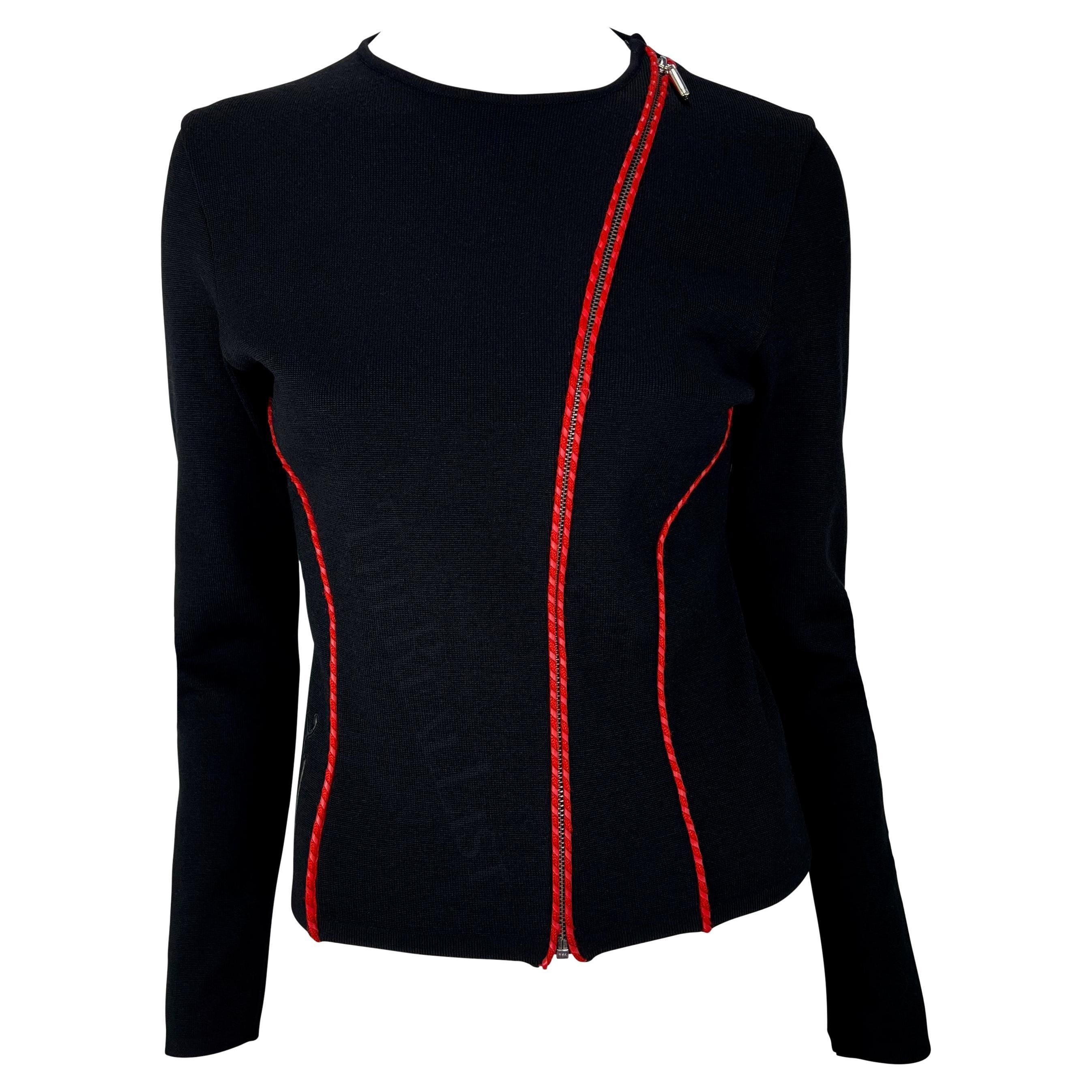 Wir präsentieren ein fabelhaftes schwarzes Pulloveroberteil von Gianni Versace, entworfen von Donatella Versace. Dieser schwarze Pullover aus den frühen 2000er Jahren zeichnet sich durch einen asymmetrischen Reißverschluss auf der Vorderseite, rote