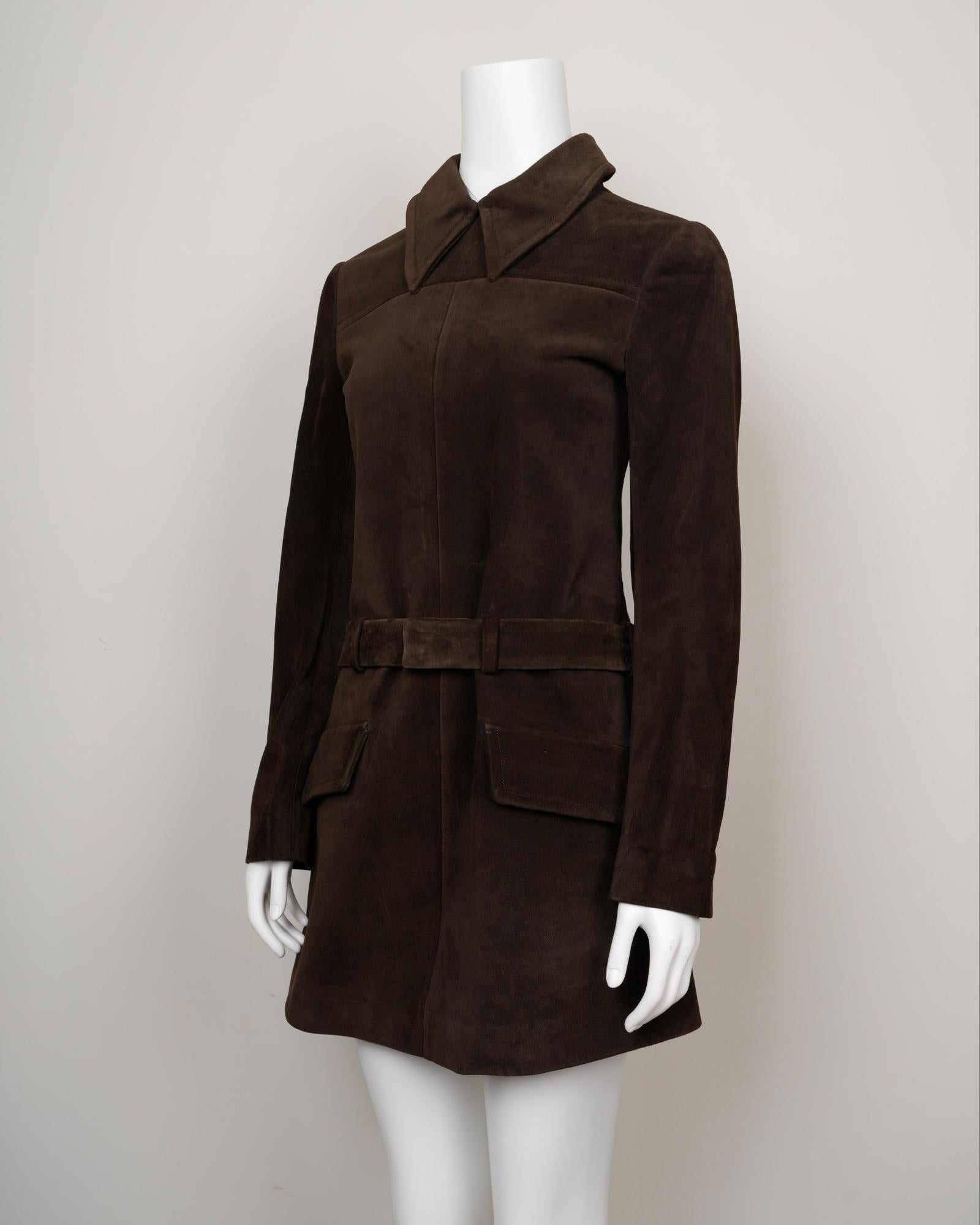 This chocolate brown suede shirtdress in Size S (US4 / IT40) is an archival piece from Miu Miu’s early 2000s collection, designed under the razor-sharp vision of Miuccia Prada. The cut combines structure and softness: a shirt-style collar, long