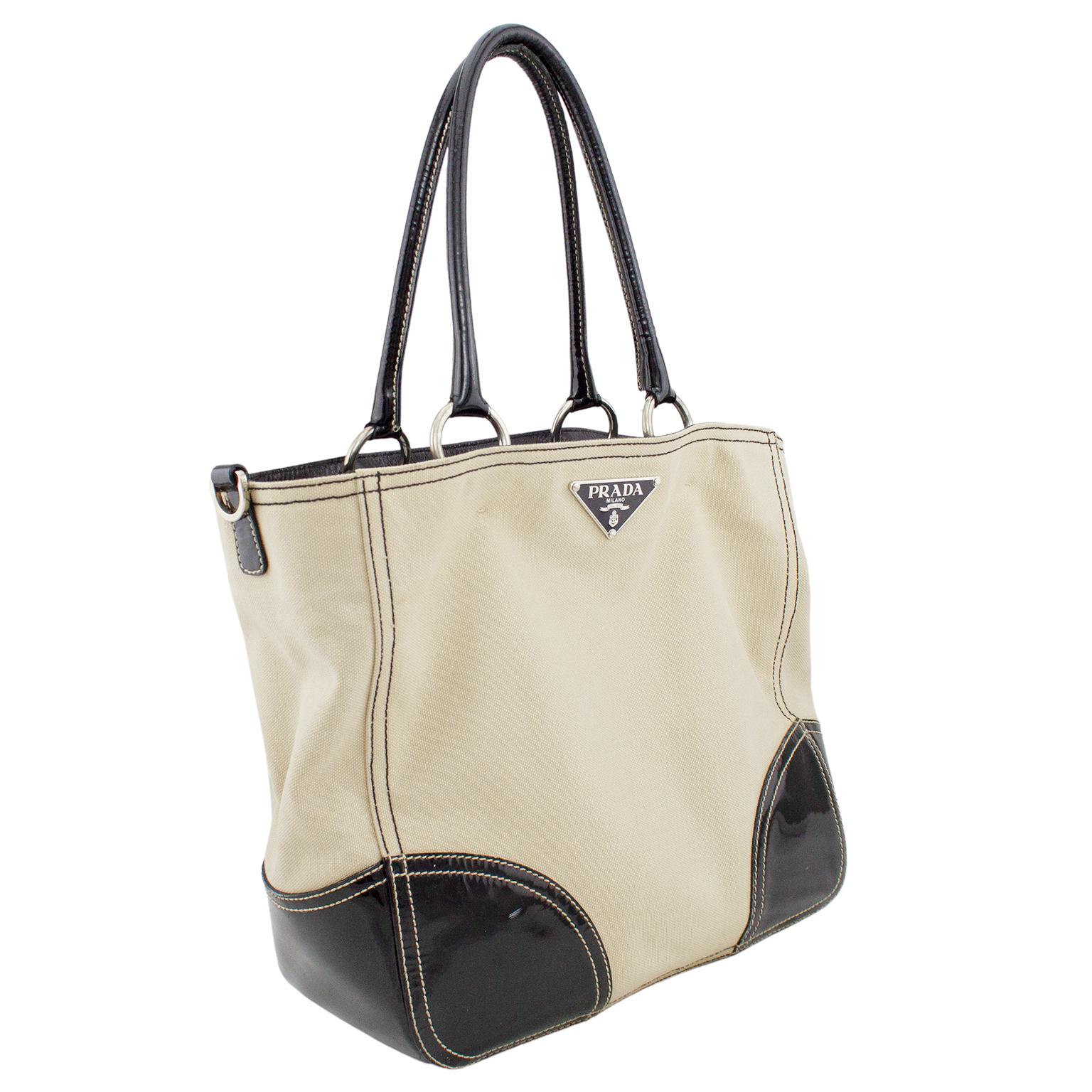 Prada tote from the early 2000s. Beige canvas with contrasting black patent leather accents and silver hardware. Black top stitching on the beige canvas and beige top stitching on the black patent leather. Black fabric interior with all over Prada