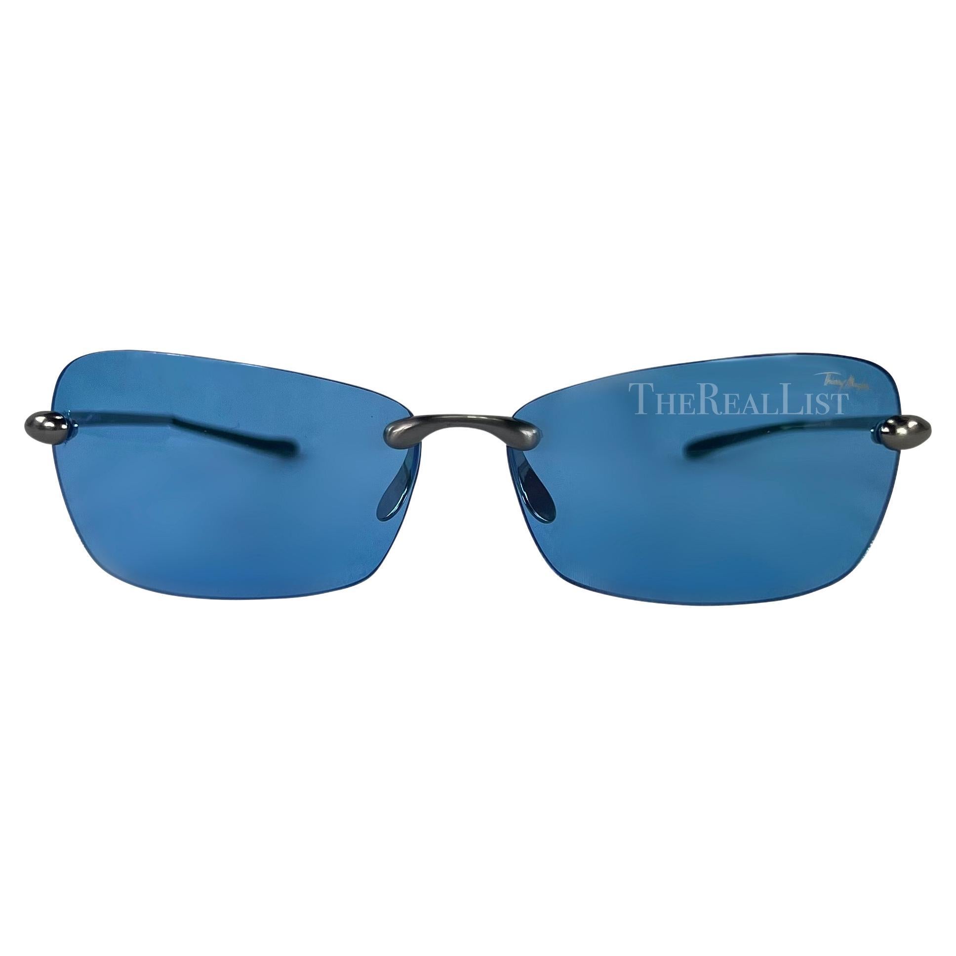 Presenting a pair of blue rimless Thierry Mugler sunglasses, designed by Manfred Mugler. From the early 2000s, these sunglasses feature rectangular lenses with a slight cat eye and are made complete with chrome metal arms.

Approximate
