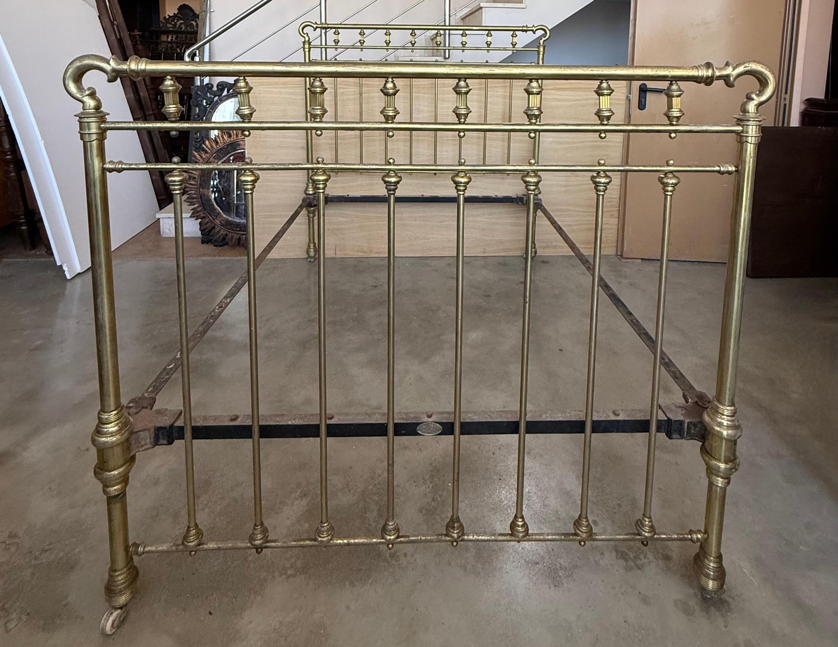 Lit en laiton ancien français, élégant et inhabituel. De forme rectangulaire mais avec des angles arrondis lisses, des rails tubulaires et des épis de faîtage en forme de boule. Un lit de bonne qualité et bien fait. En bon état, robuste et solide