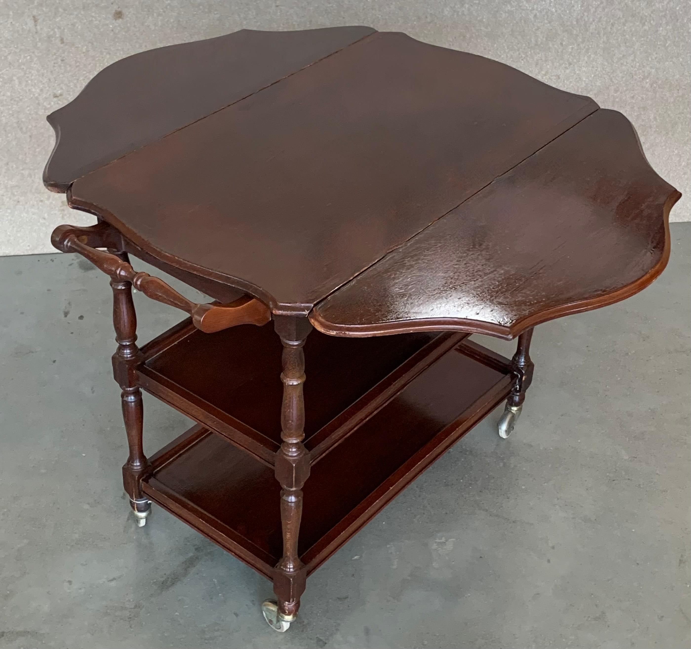 Very cool serving cart made from walnut with three trays. The two leafs are easily and quickly folding and the cart is convertible in a functional coffee tea or table that you love it. You also can fold the handle.
It has wheels that works