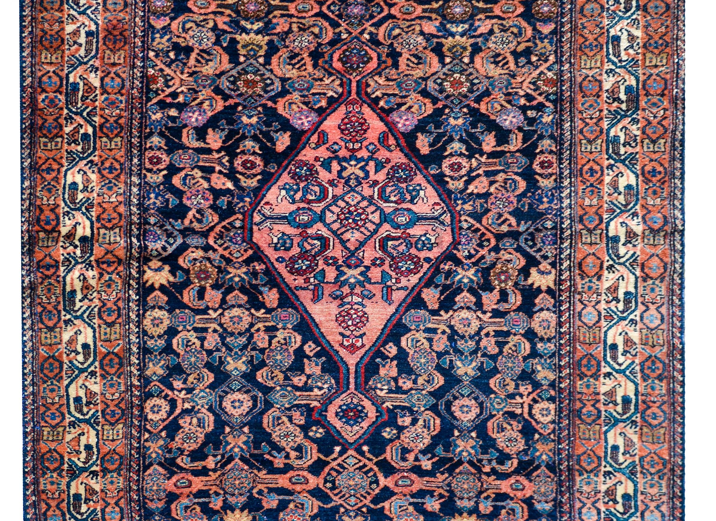 A fantastic early 20th century Persian Bibikibad rug with a central diamond floral medallion amidst a field of stylized flowers and vines, all woven in wonderful pinks, indigos, crimsons, and creams against a dark indigo background, and surrounded